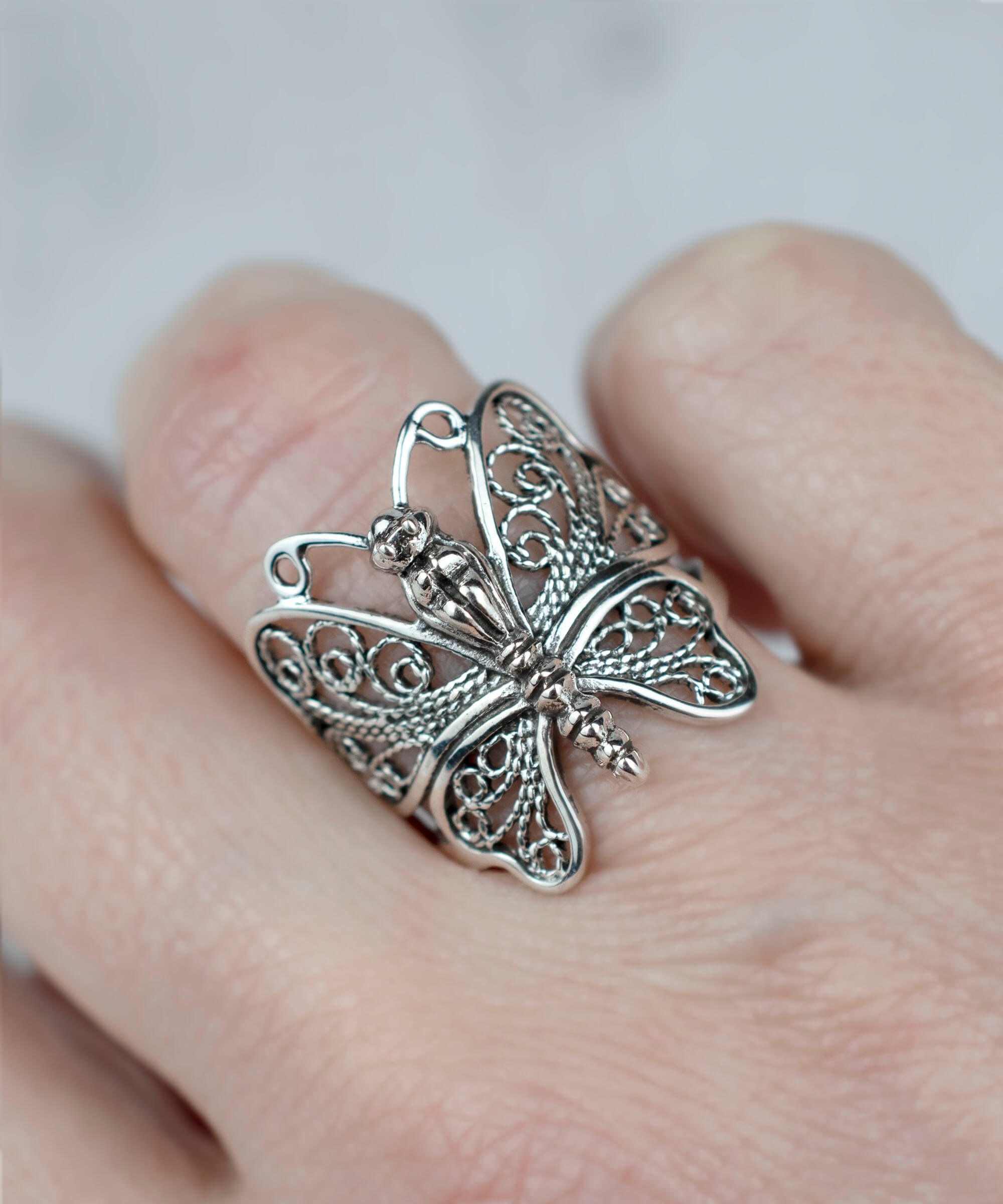 A stunning sterling silver statement ring featuring an intricate filigree butterfly design, elegantly polished and oxidized.