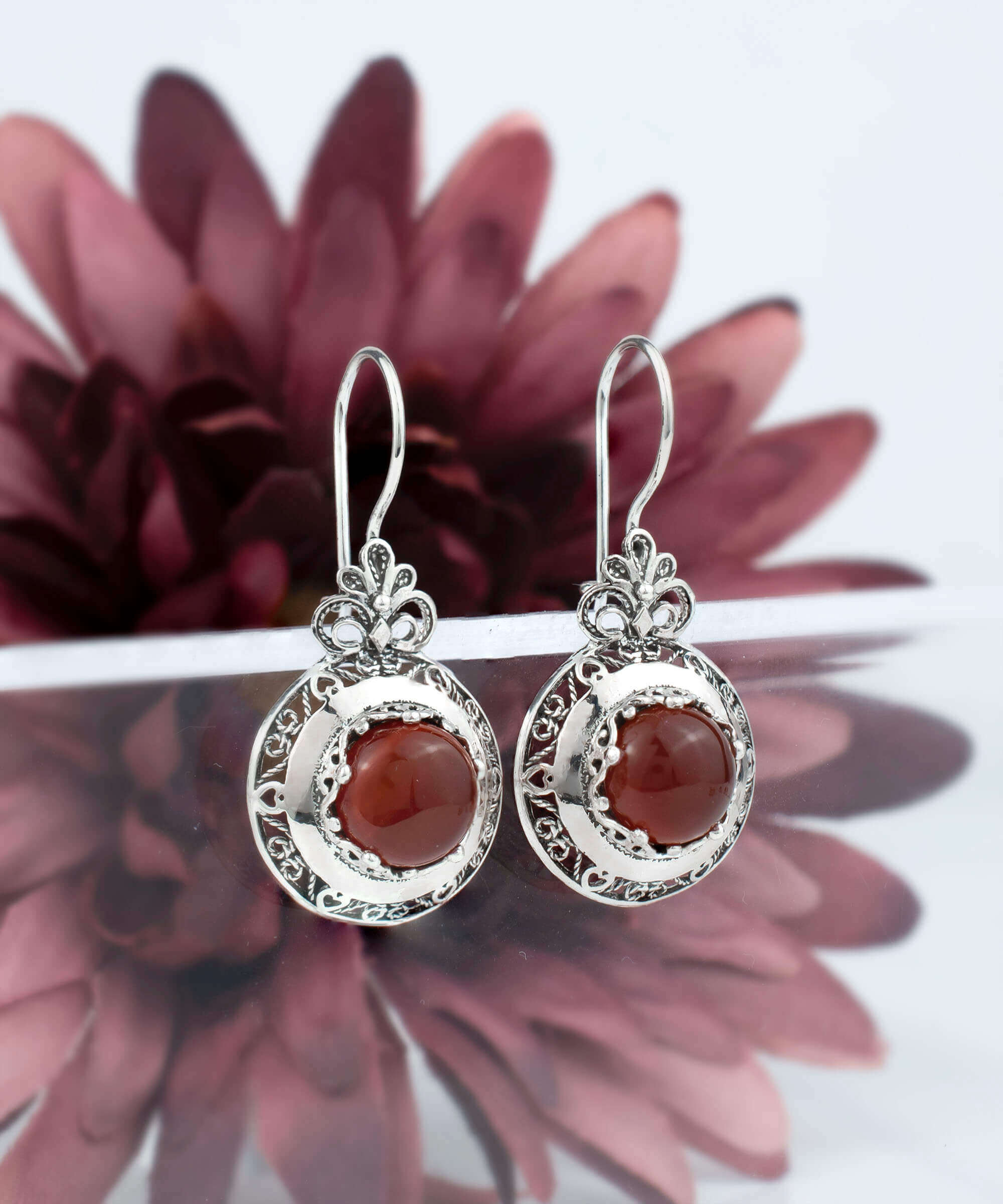 Handmade silver drop earrings featuring intricate filigree floral design and warm Carnelian gemstones, elegantly displayed in a luxurious gift box.