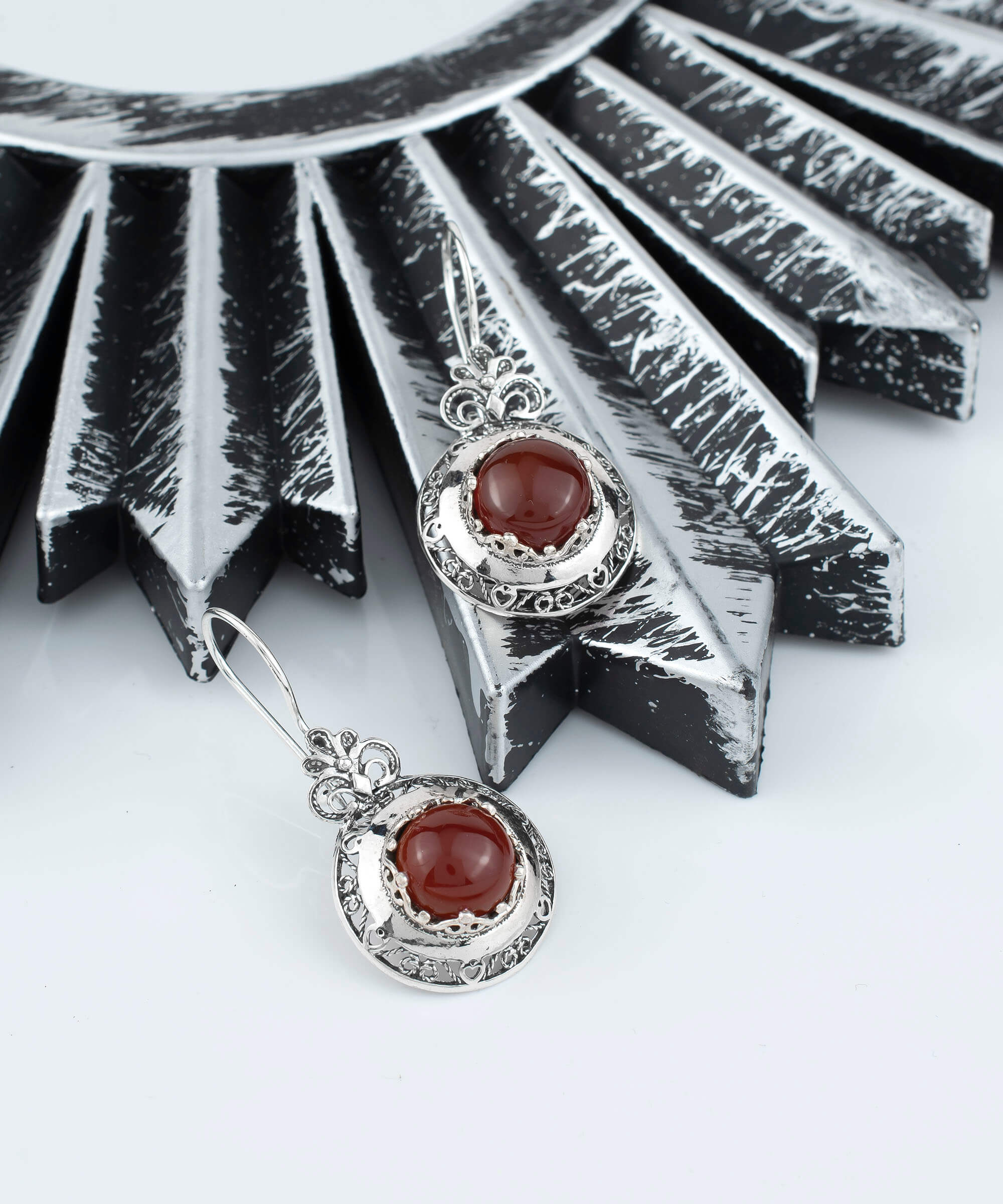 Handmade silver drop earrings featuring intricate filigree floral design and warm Carnelian gemstones, elegantly displayed in a luxurious gift box.