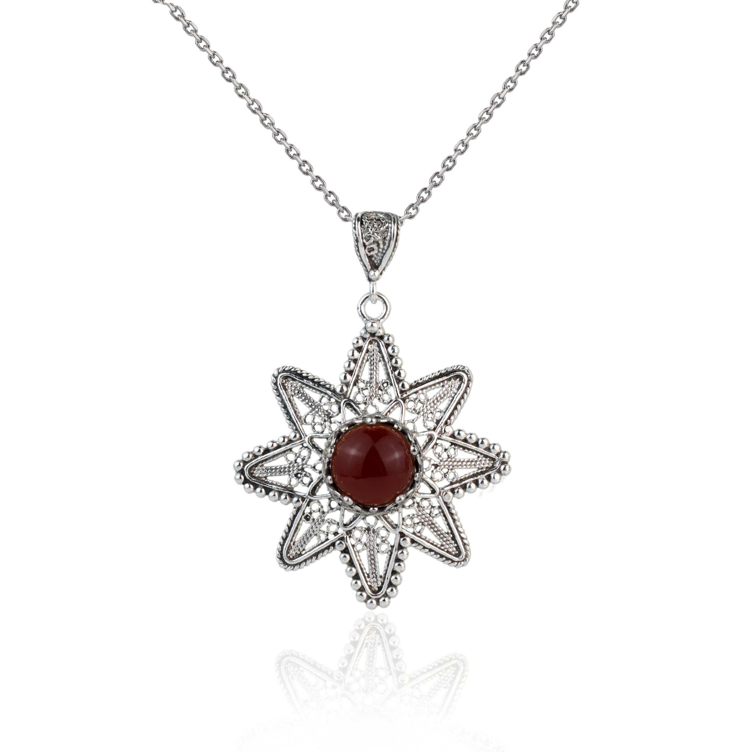 A stunning silver pendant featuring a sunflower design with a natural carnelian gemstone at the center, showcasing intricate filigree art.