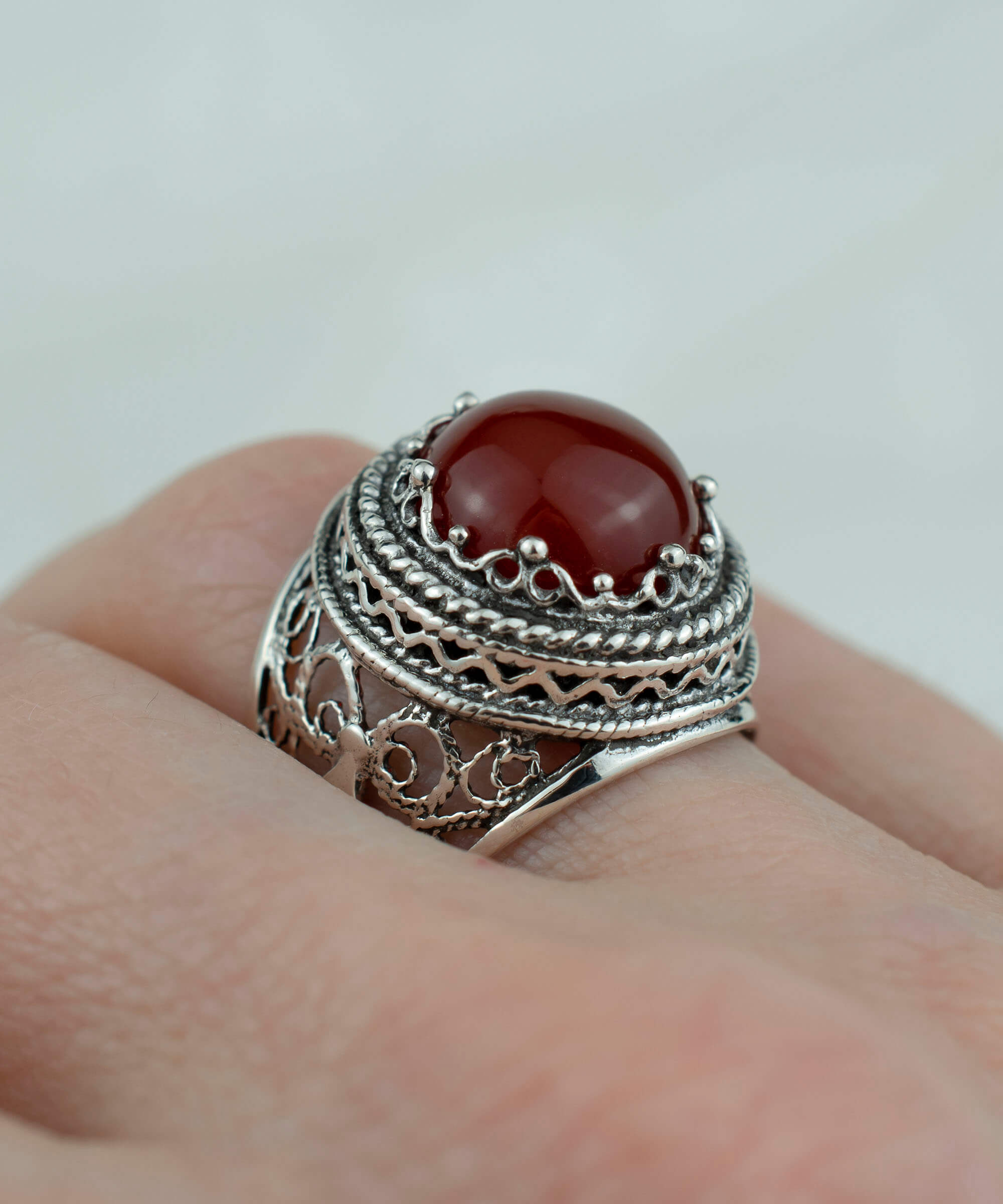 A stunning sterling silver bold ring featuring a round-cut 12mm carnelian gemstone, showcasing intricate filigree art design.