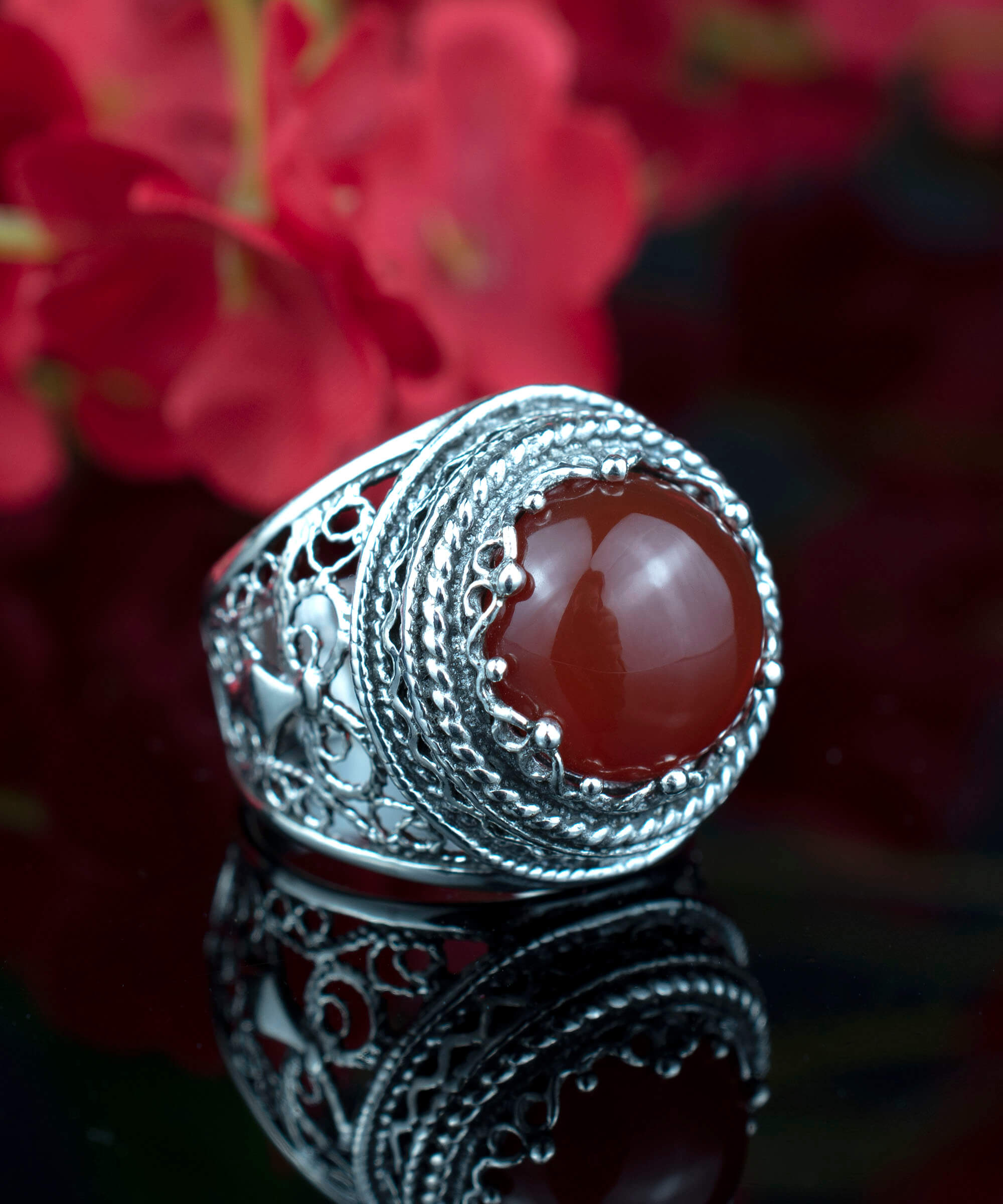 A stunning sterling silver bold ring featuring a round-cut 12mm carnelian gemstone, showcasing intricate filigree art design.