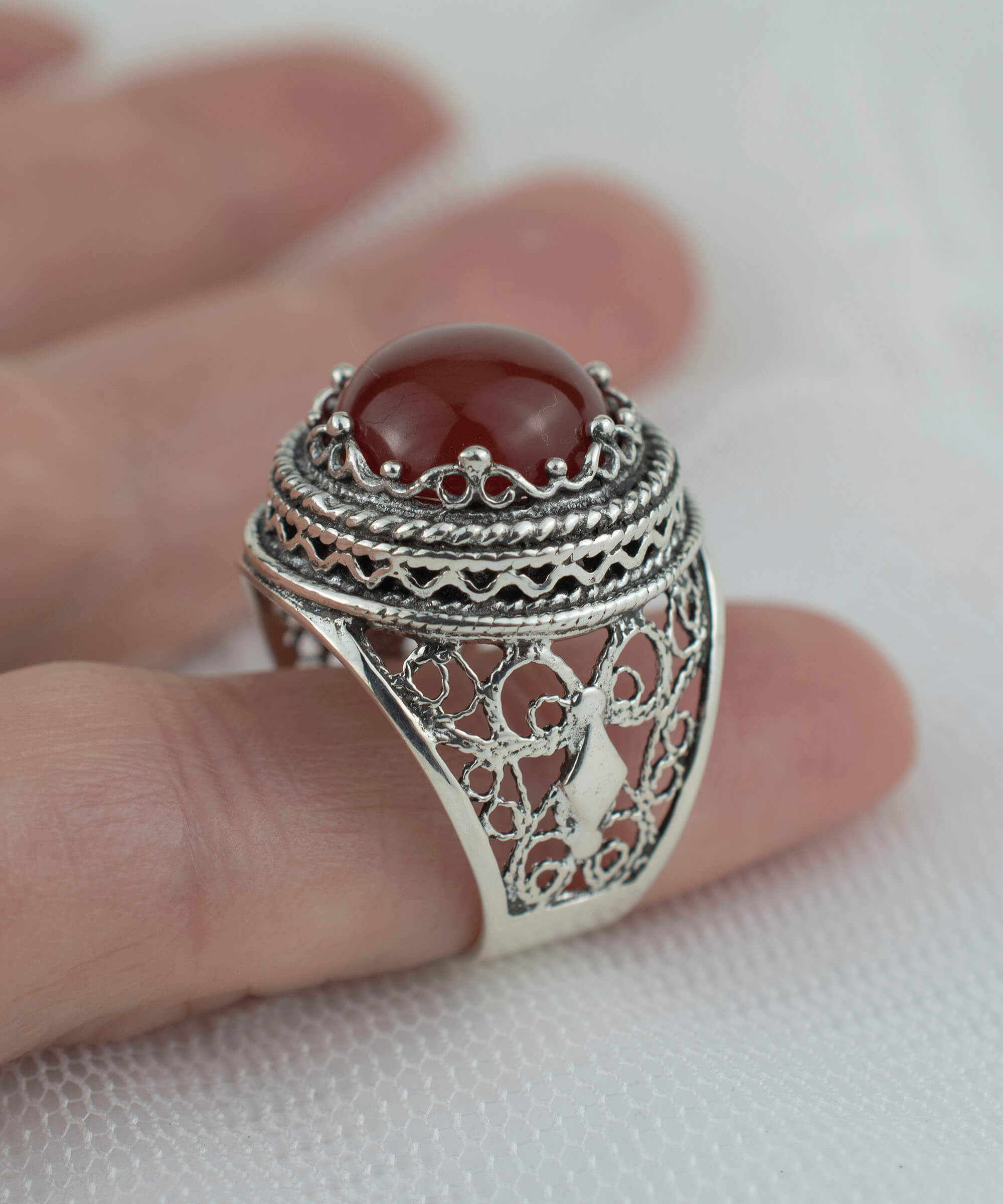 A stunning sterling silver bold ring featuring a round-cut 12mm carnelian gemstone, showcasing intricate filigree art design.