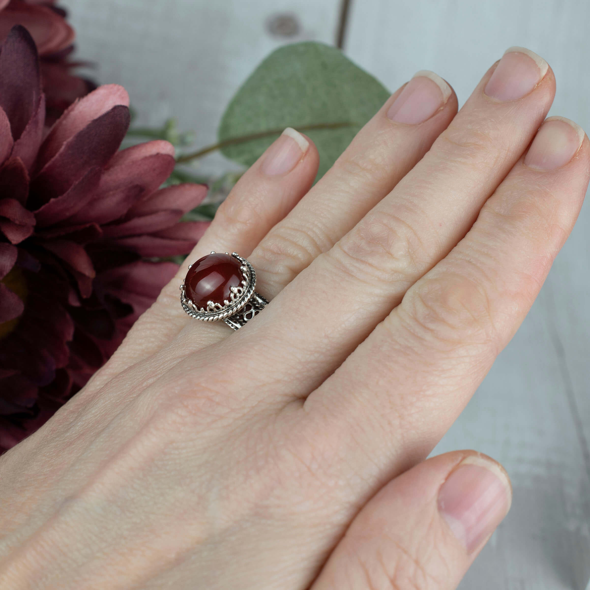 Sterling silver filigree cocktail ring featuring a round cut carnelian gemstone, showcasing intricate metalwork and a polished finish.