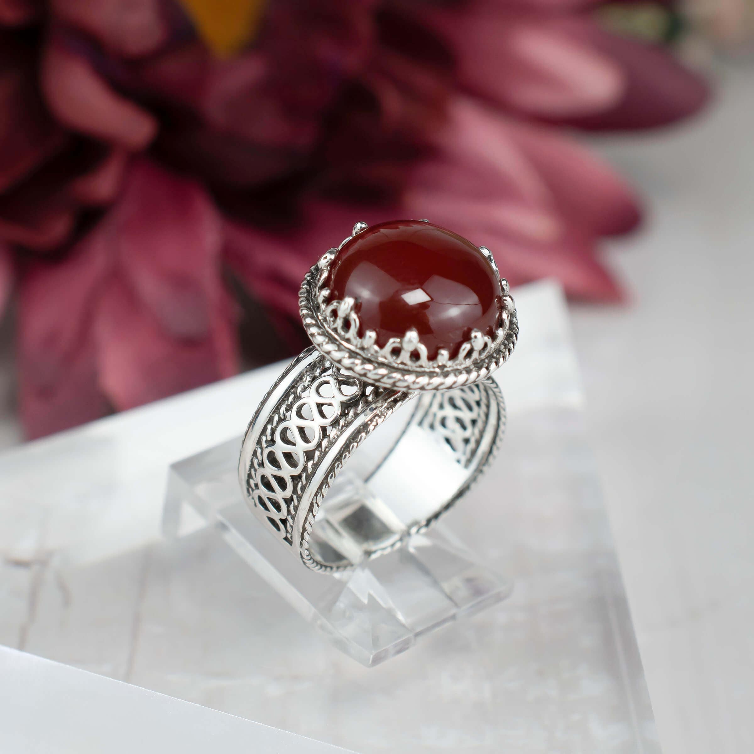 Sterling silver filigree cocktail ring featuring a round cut carnelian gemstone, showcasing intricate metalwork and a polished finish.