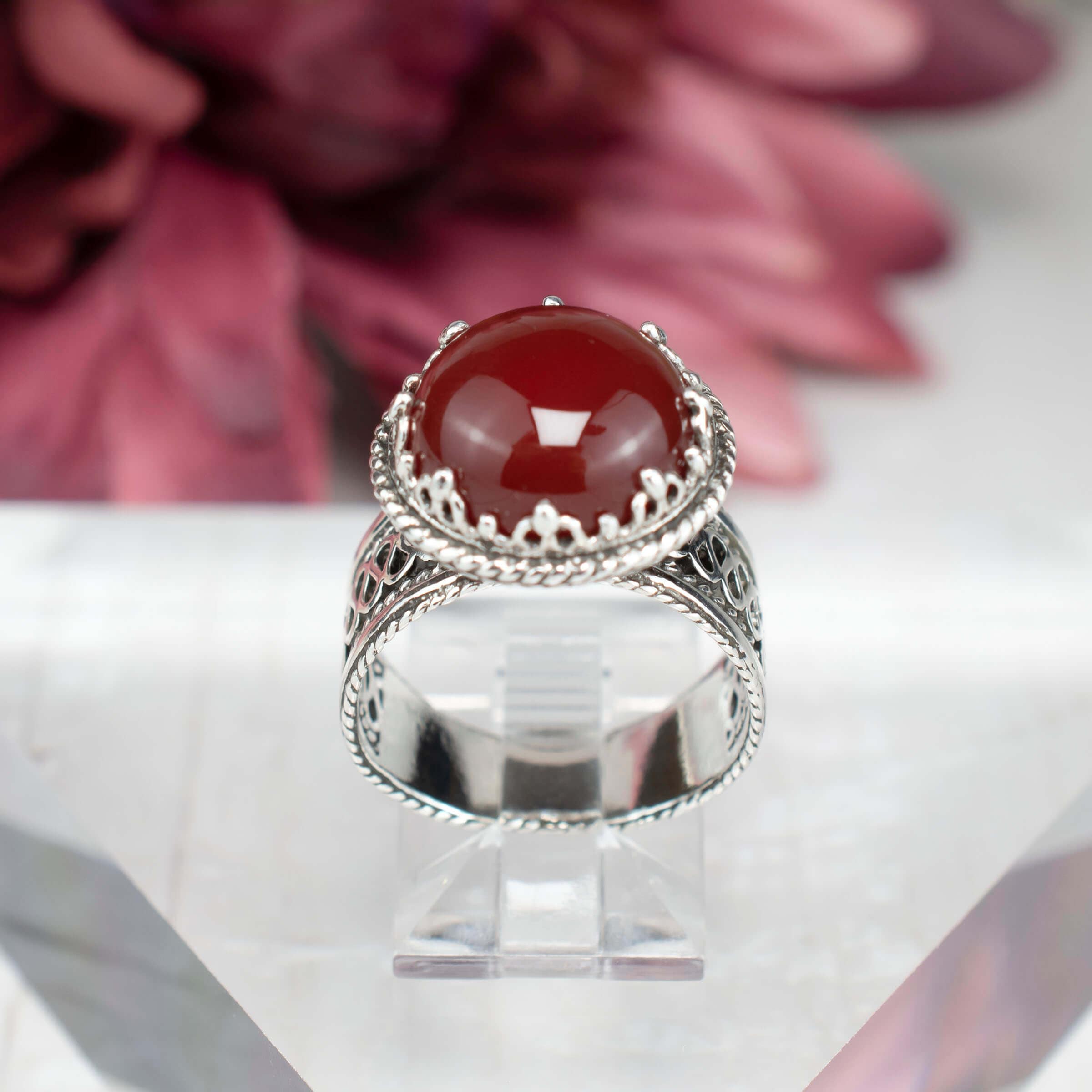 Sterling silver filigree cocktail ring featuring a round cut carnelian gemstone, showcasing intricate metalwork and a polished finish.