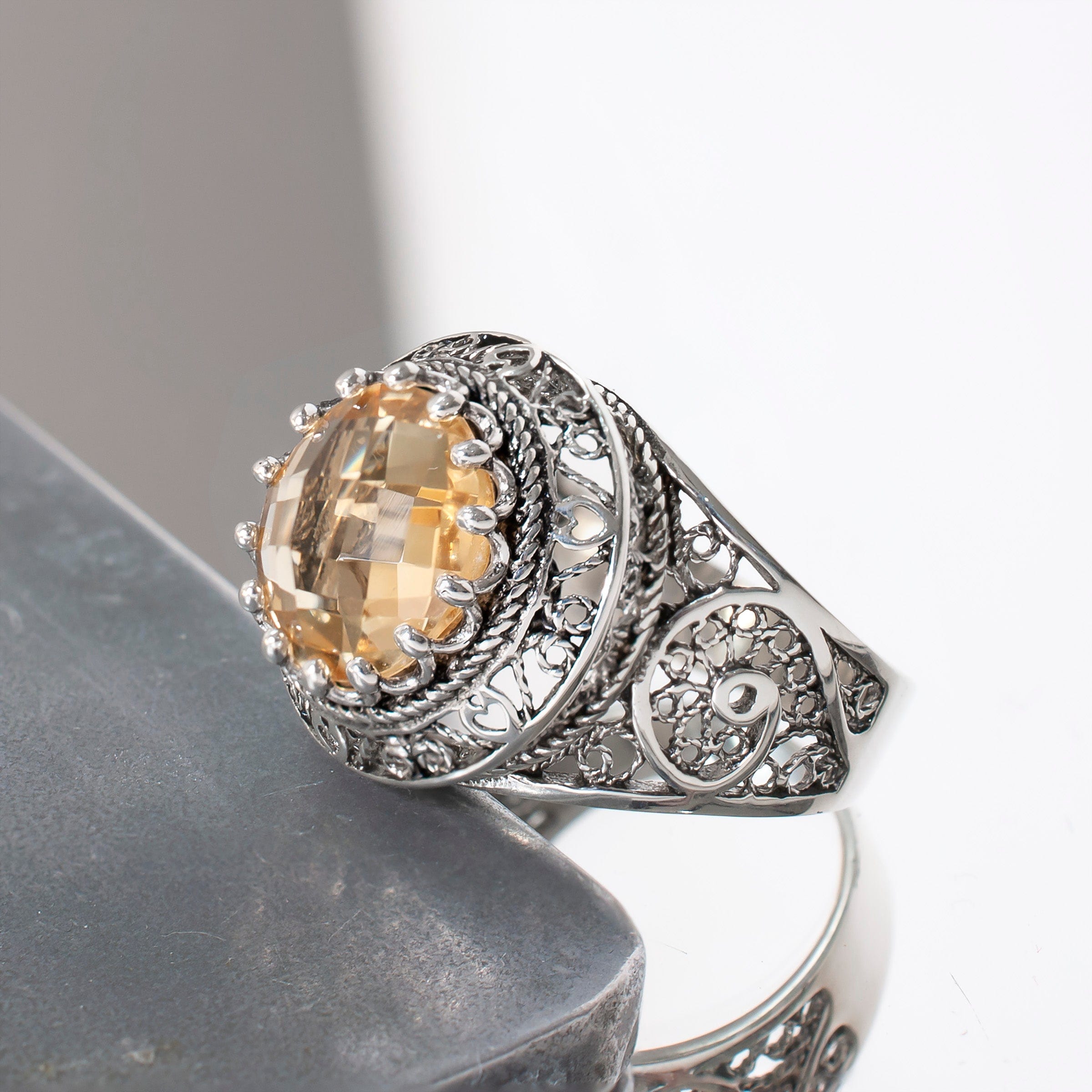 A stunning silver statement ring featuring intricate filigree design and a round faceted Citrine gemstone, elegantly displayed in a luxurious gift box.