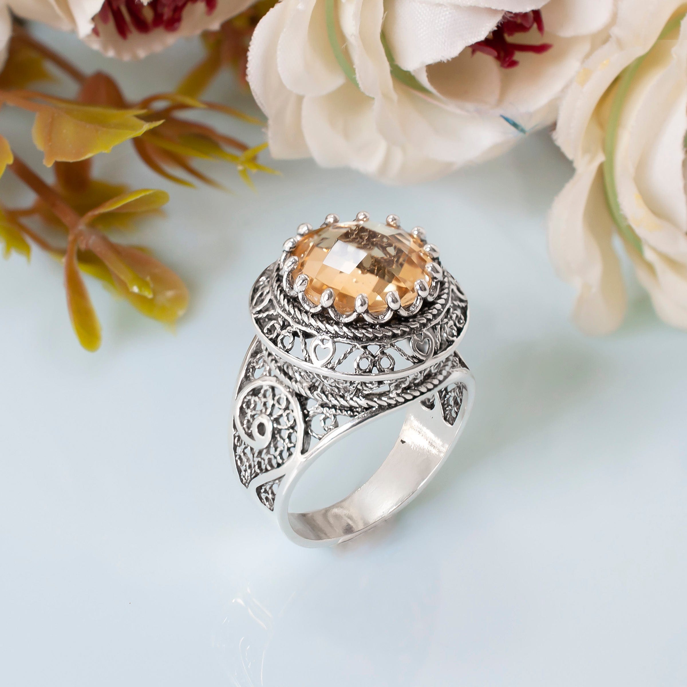 A stunning silver statement ring featuring intricate filigree design and a round faceted Citrine gemstone, elegantly displayed in a luxurious gift box.