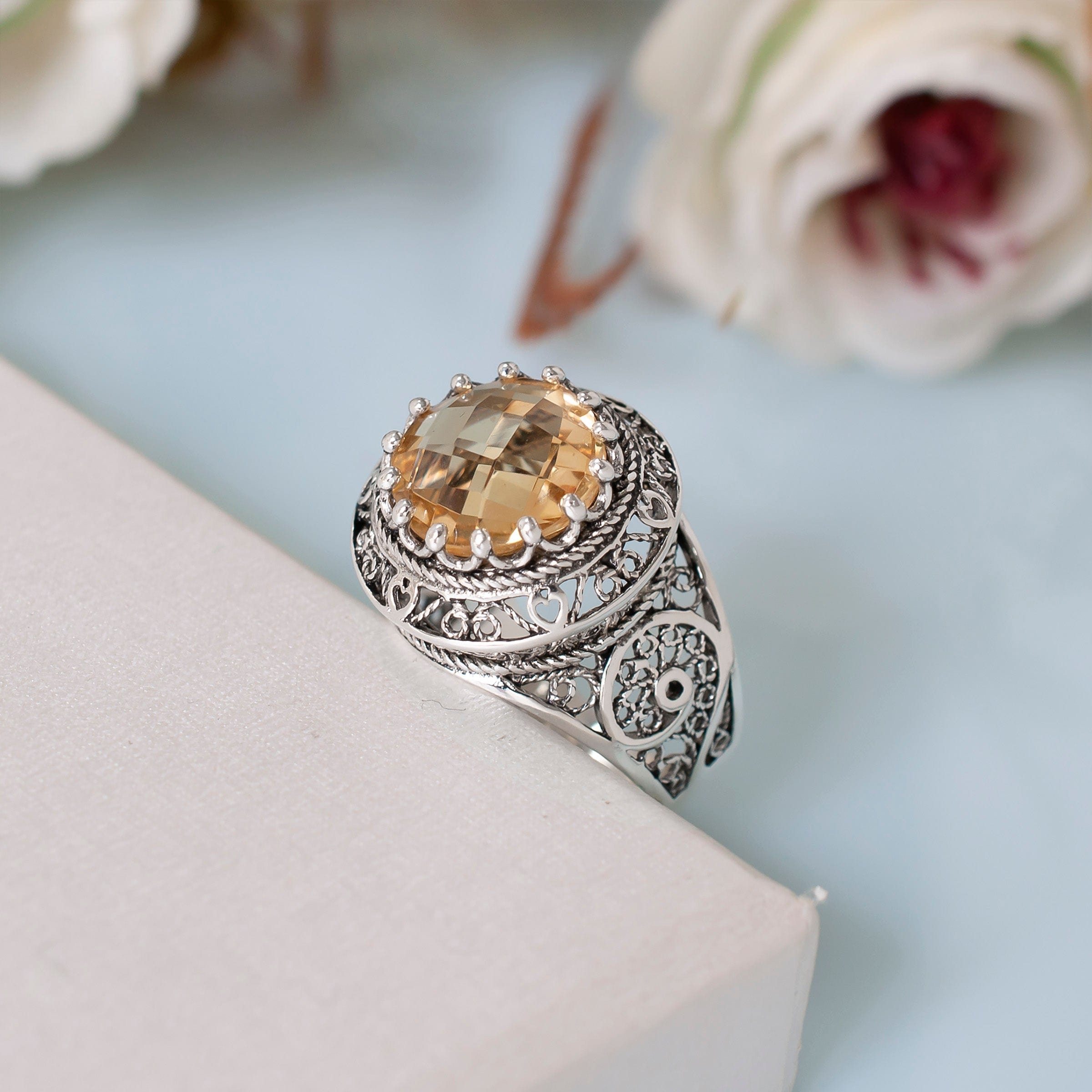 A stunning silver statement ring featuring intricate filigree design and a round faceted Citrine gemstone, elegantly displayed in a luxurious gift box.