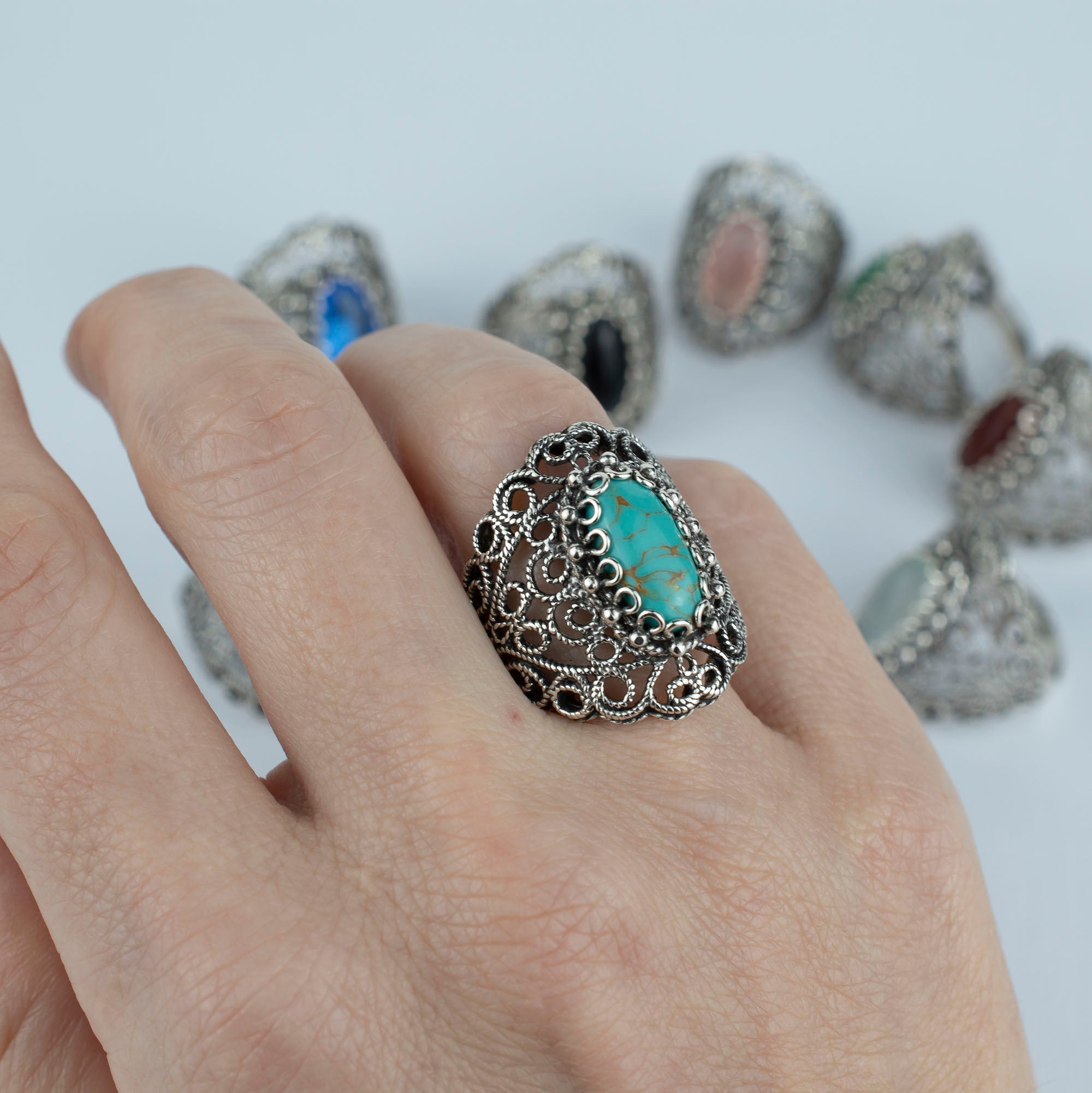 Handmade silver statement ring featuring intricate filigree design and a copper turquoise gemstone centerpiece.