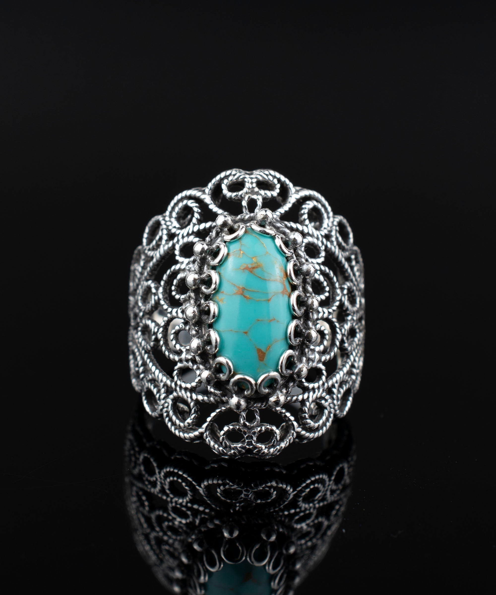 Handmade silver statement ring featuring intricate filigree design and a copper turquoise gemstone centerpiece.