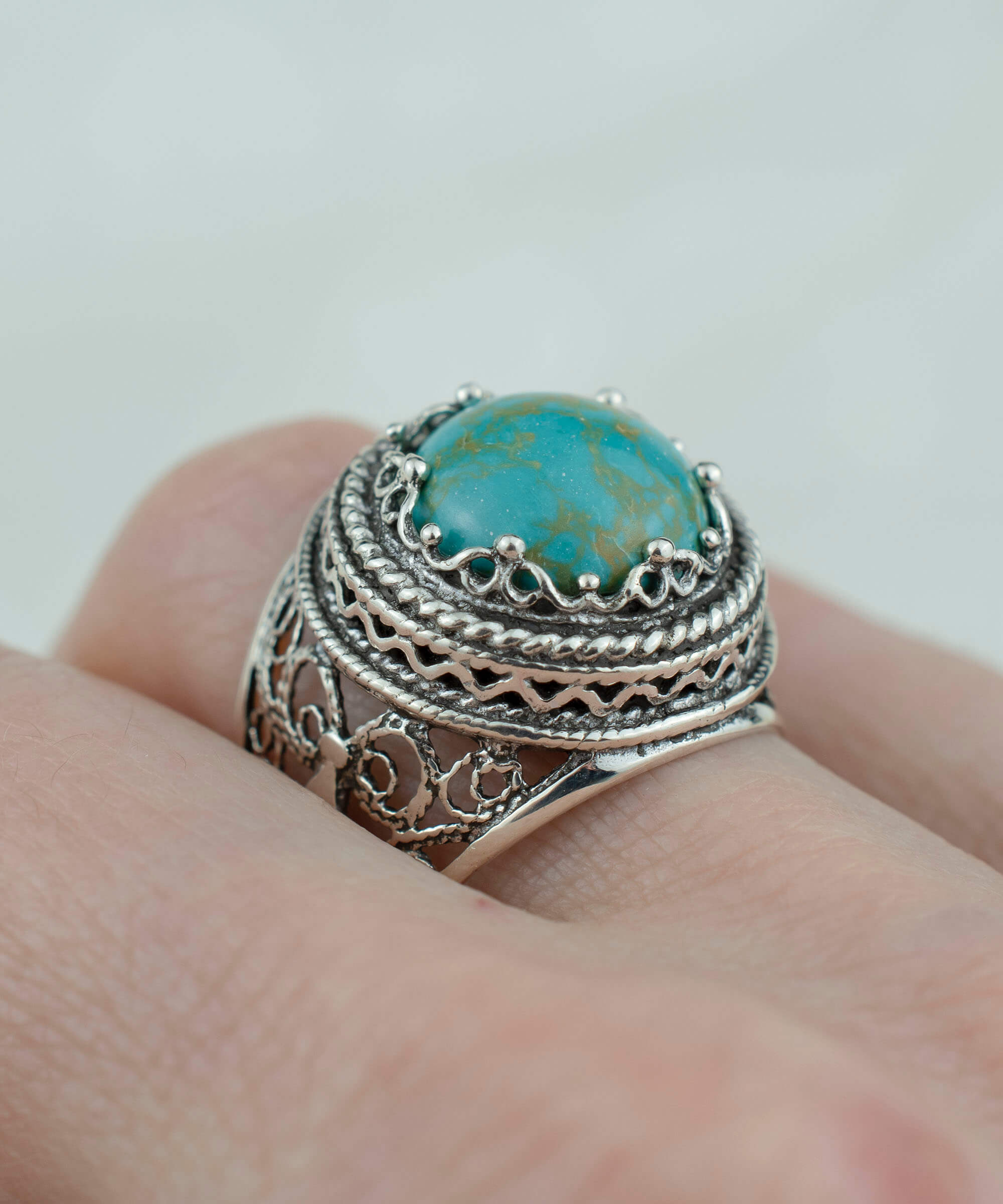 A stunning silver ring featuring intricate filigree art and a round 12mm copper turquoise gemstone, showcasing a blend of modern and traditional design.