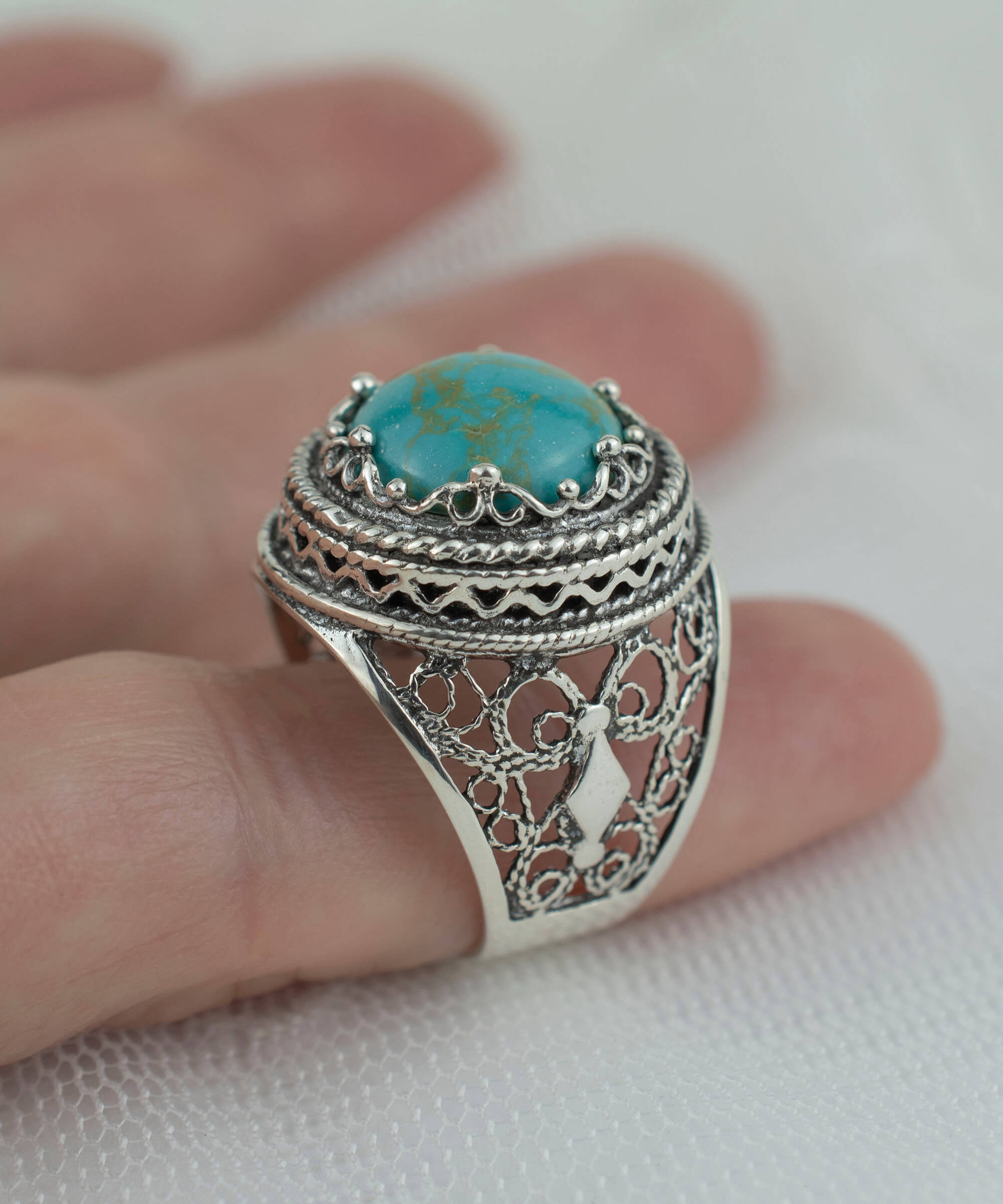 A stunning silver ring featuring intricate filigree art and a round 12mm copper turquoise gemstone, showcasing a blend of modern and traditional design.