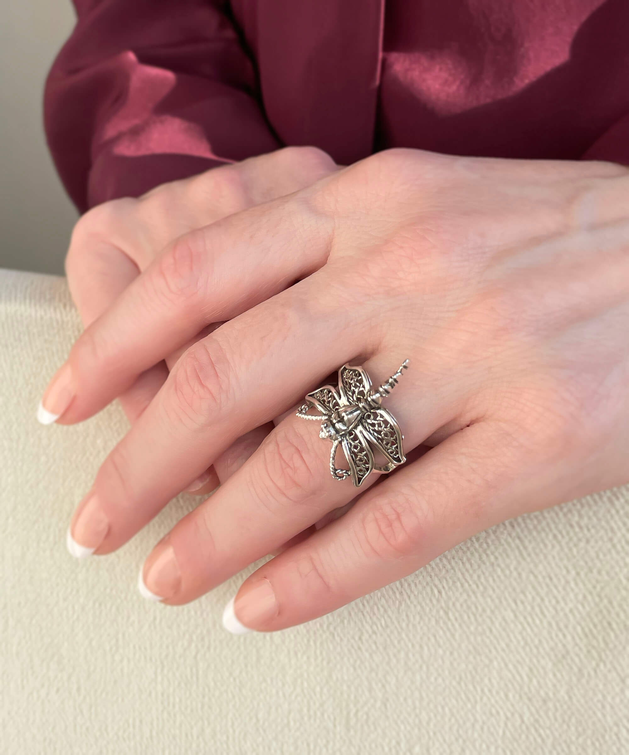 A stunning silver cocktail ring featuring an intricate dragonfly filigree design, showcasing delicate metal strands and a polished finish.