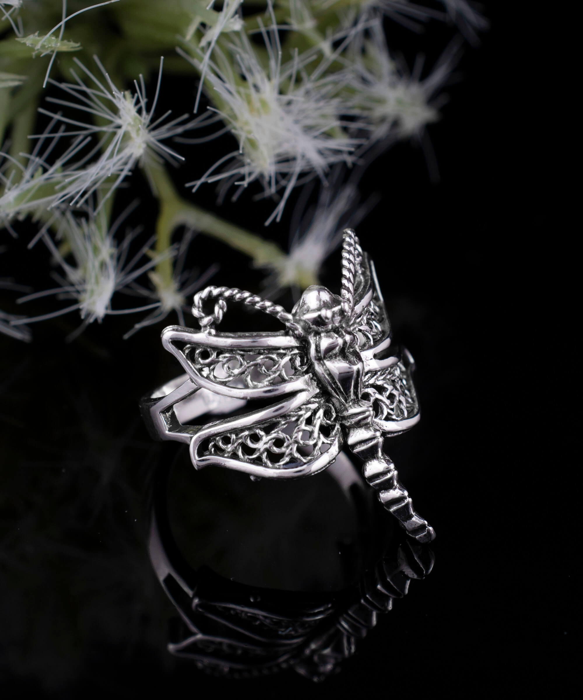 A stunning silver cocktail ring featuring an intricate dragonfly filigree design, showcasing delicate metal strands and a polished finish.