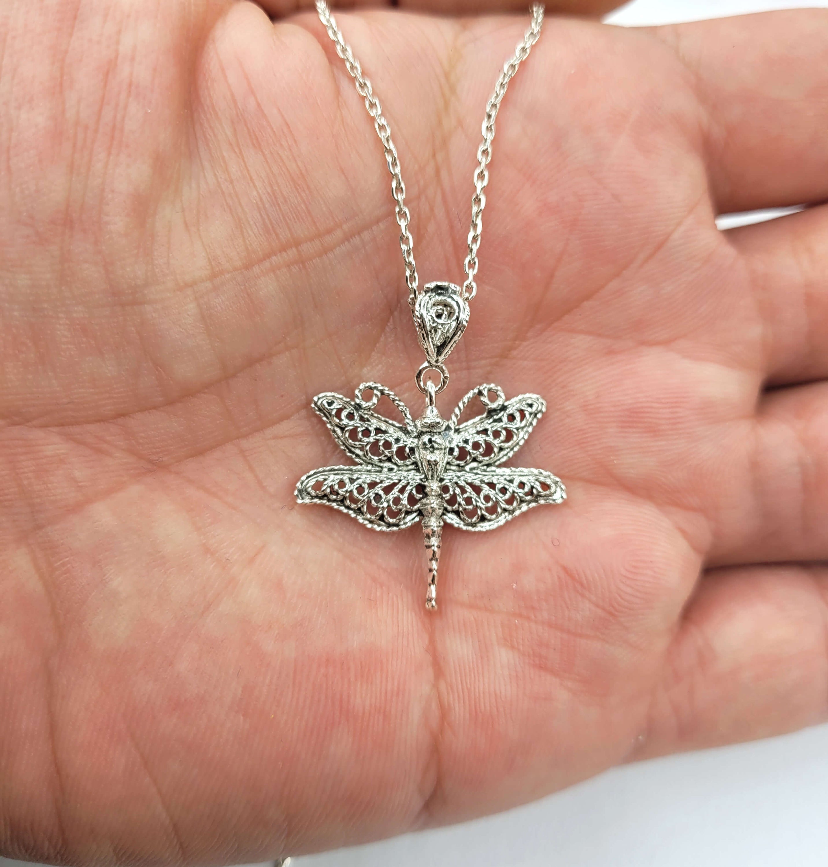 Sterling silver pendant necklace featuring a delicate filigree dragonfly design, showcasing intricate craftsmanship.