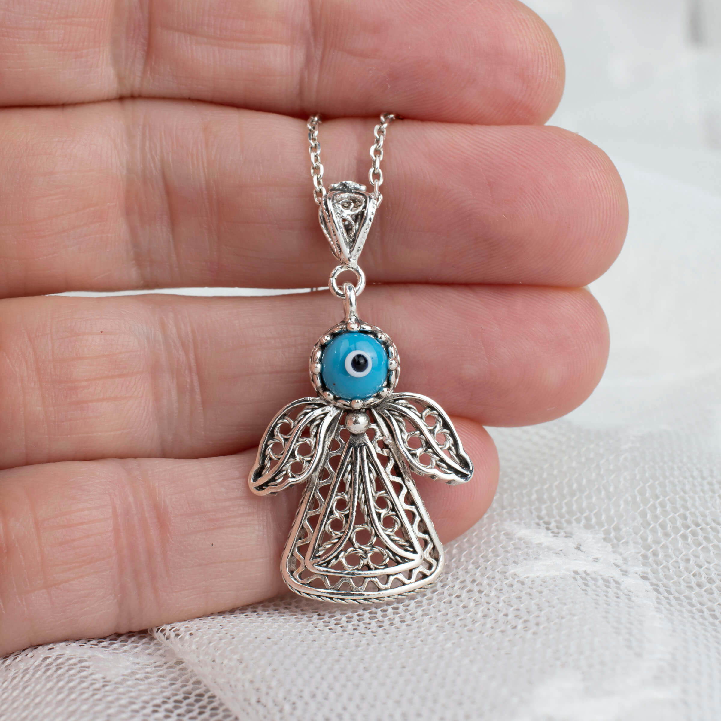 Sterling silver filigree evil eye angel pendant necklace with intricate design and cabochon cut evil eye.