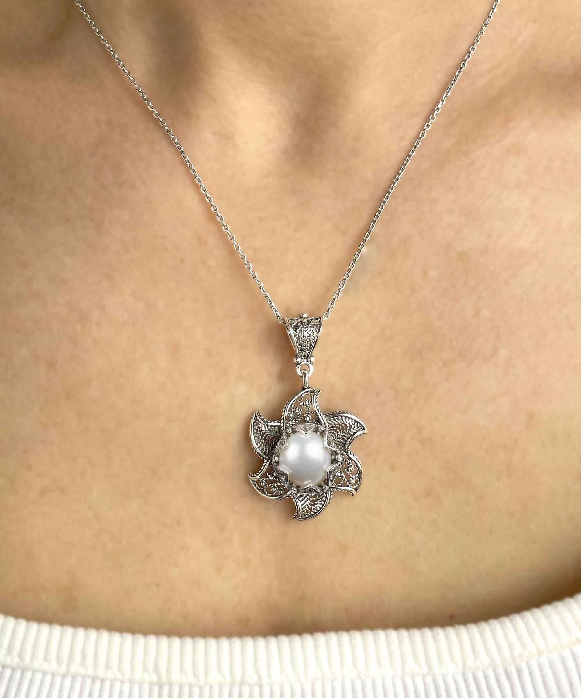 A stunning silver necklace featuring a blossoming lotus flower pendant with a central freshwater pearl, elegantly designed in filigree art.