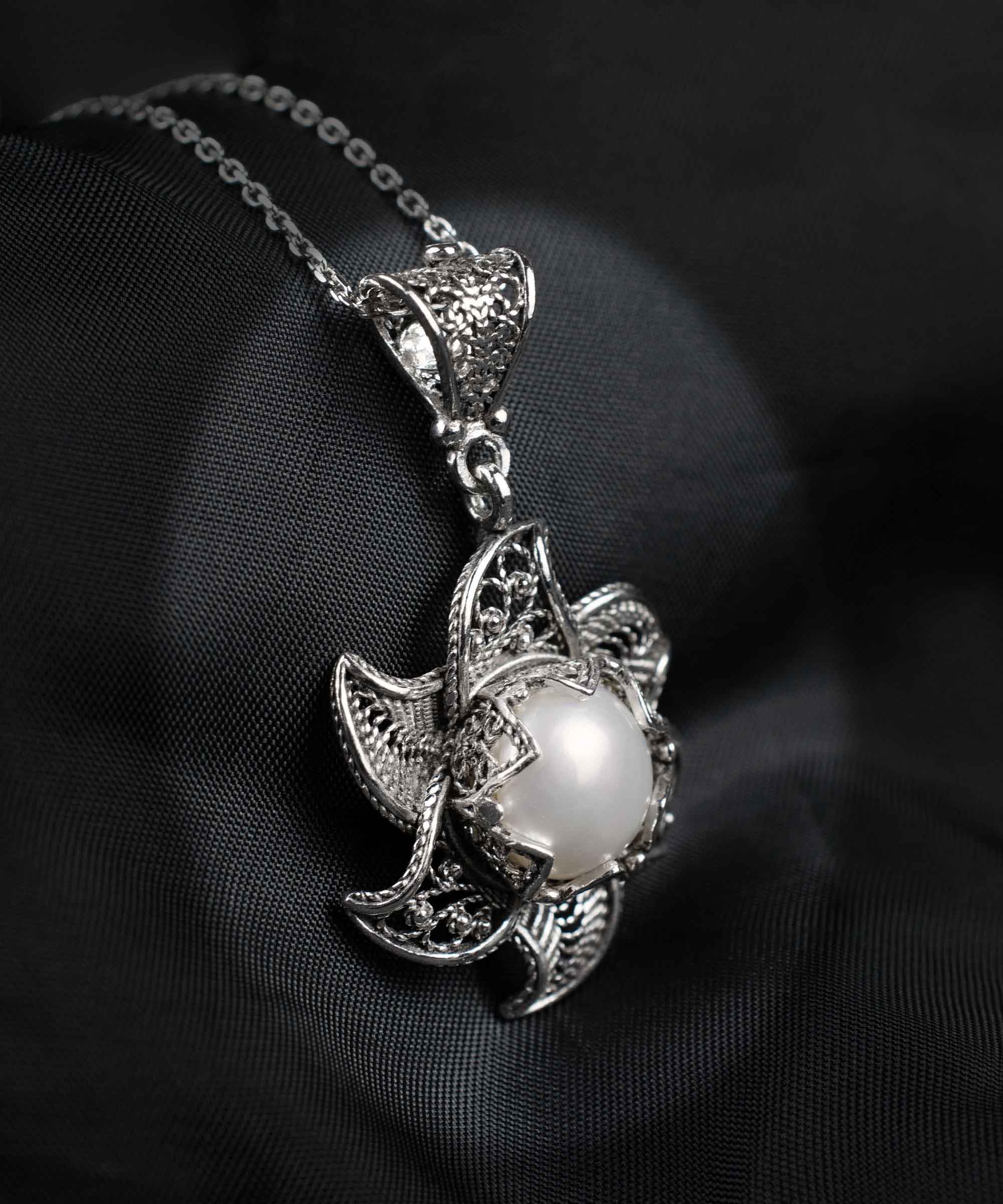 A stunning silver necklace featuring a blossoming lotus flower pendant with a central freshwater pearl, elegantly designed in filigree art.