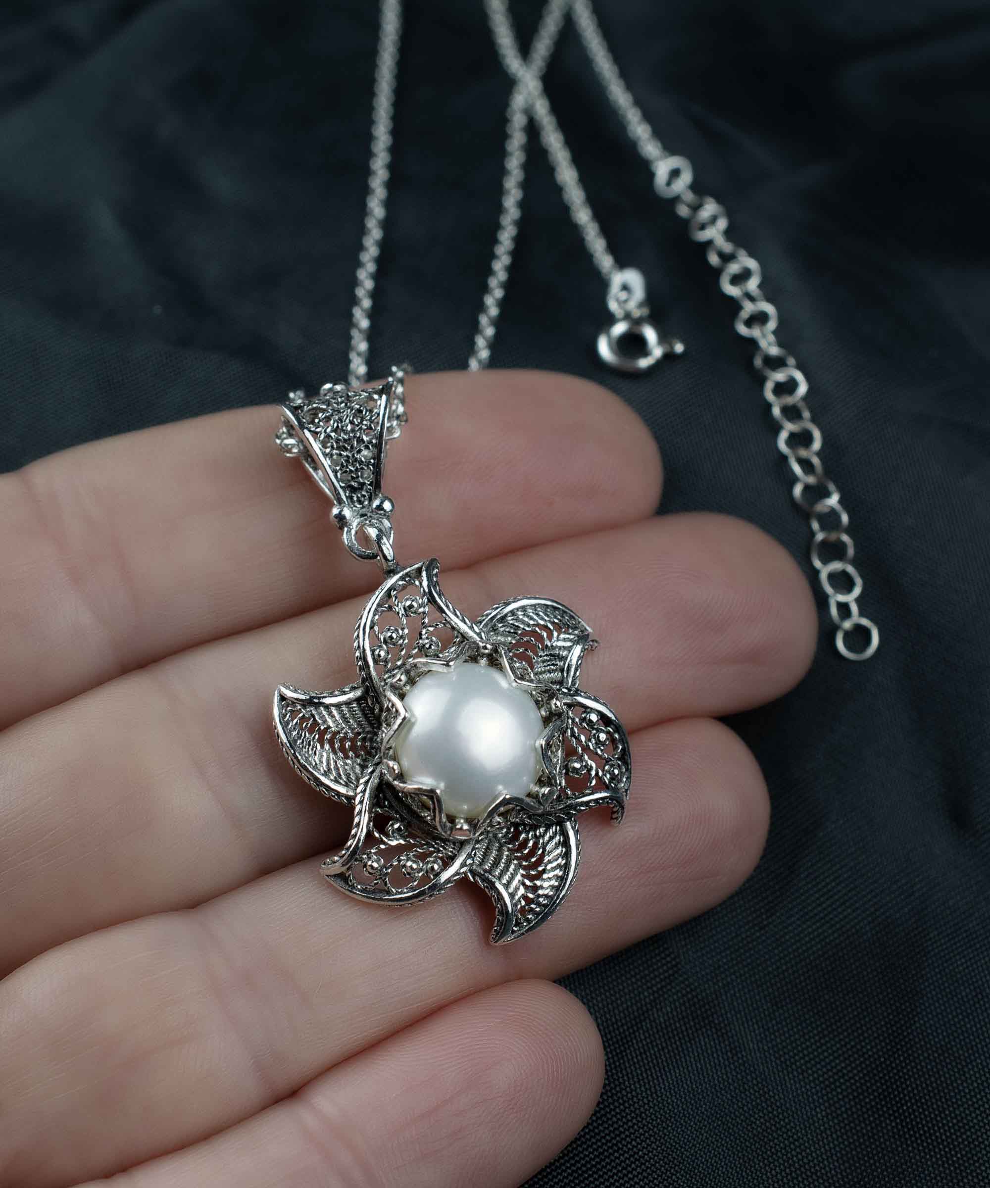 A stunning silver necklace featuring a blossoming lotus flower pendant with a central freshwater pearl, elegantly designed in filigree art.