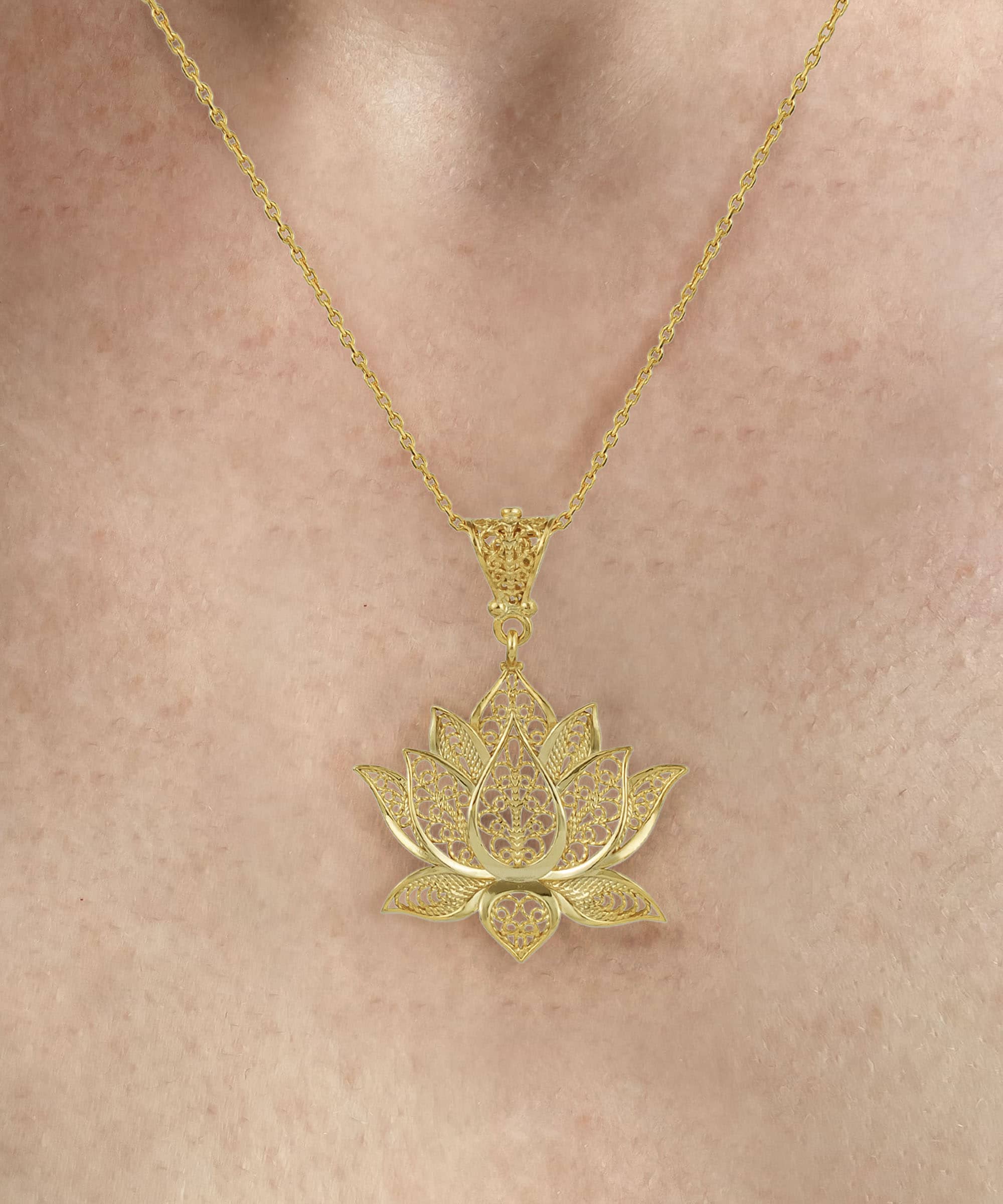 Elegant gold plated silver lotus flower pendant necklace with intricate filigree design, displayed on a soft velvet background.