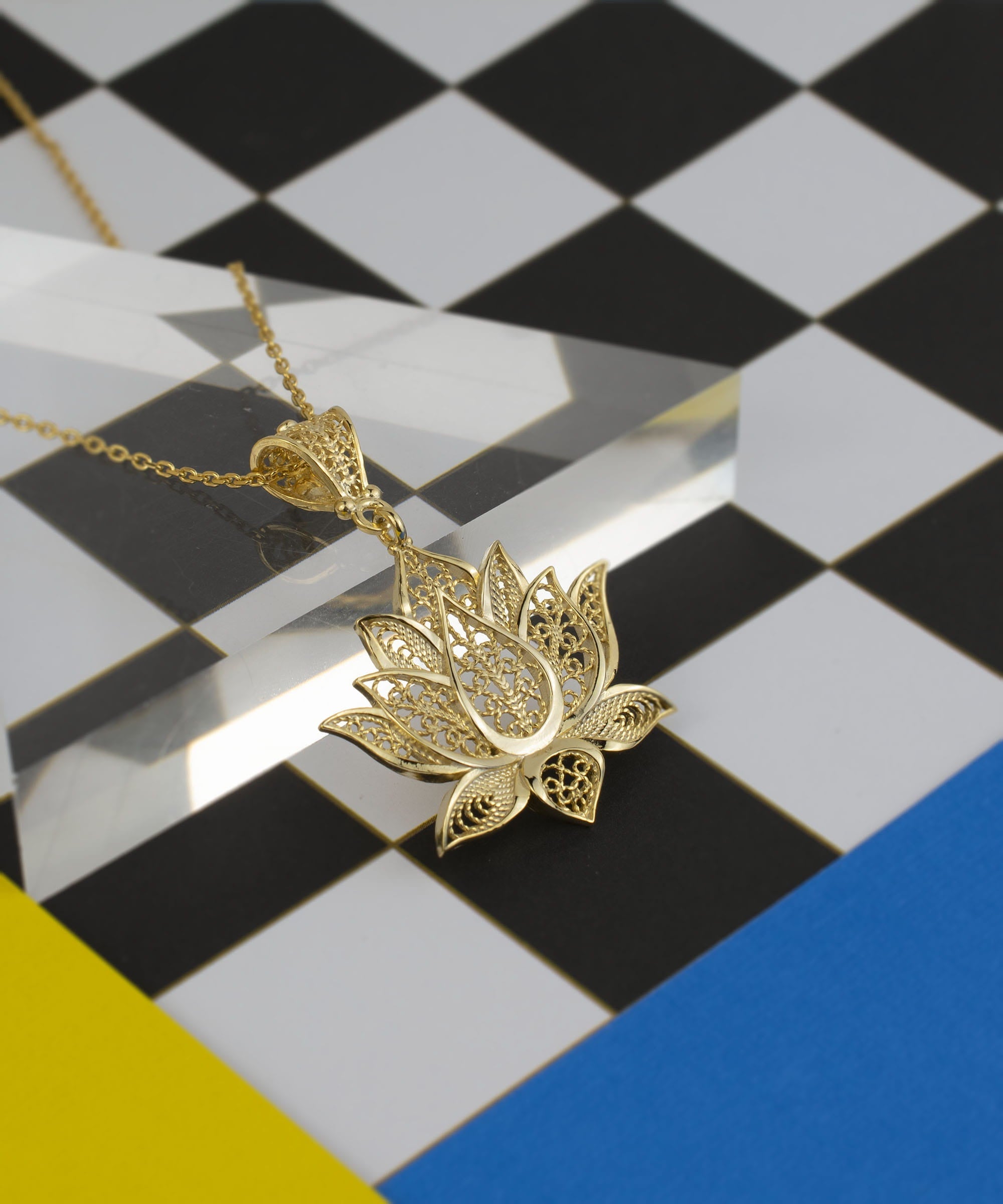 Elegant gold plated silver lotus flower pendant necklace with intricate filigree design, displayed on a soft velvet background.