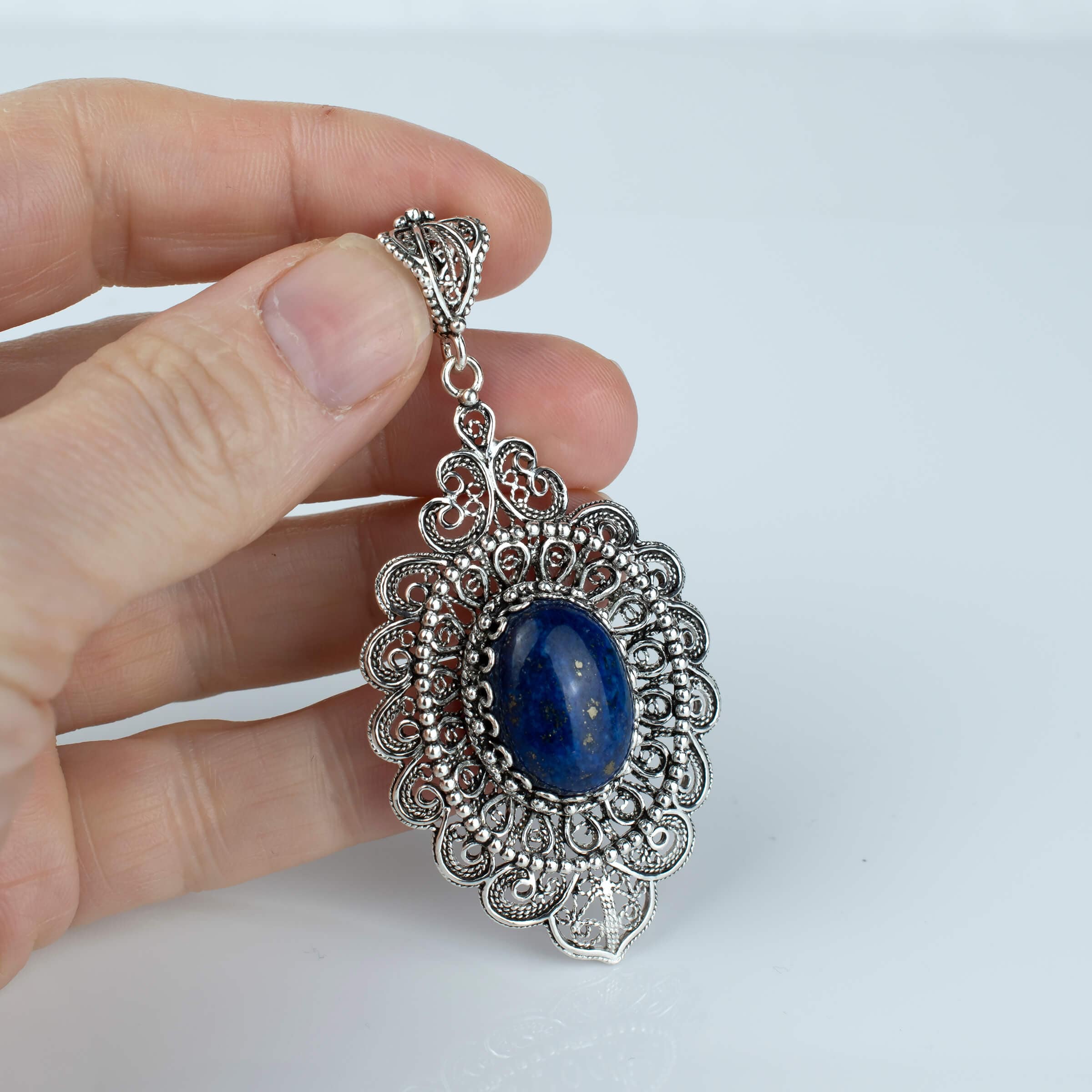 Elegant sterling silver pendant necklace featuring intricate floral filigree design and a stunning lapis lazuli gemstone.