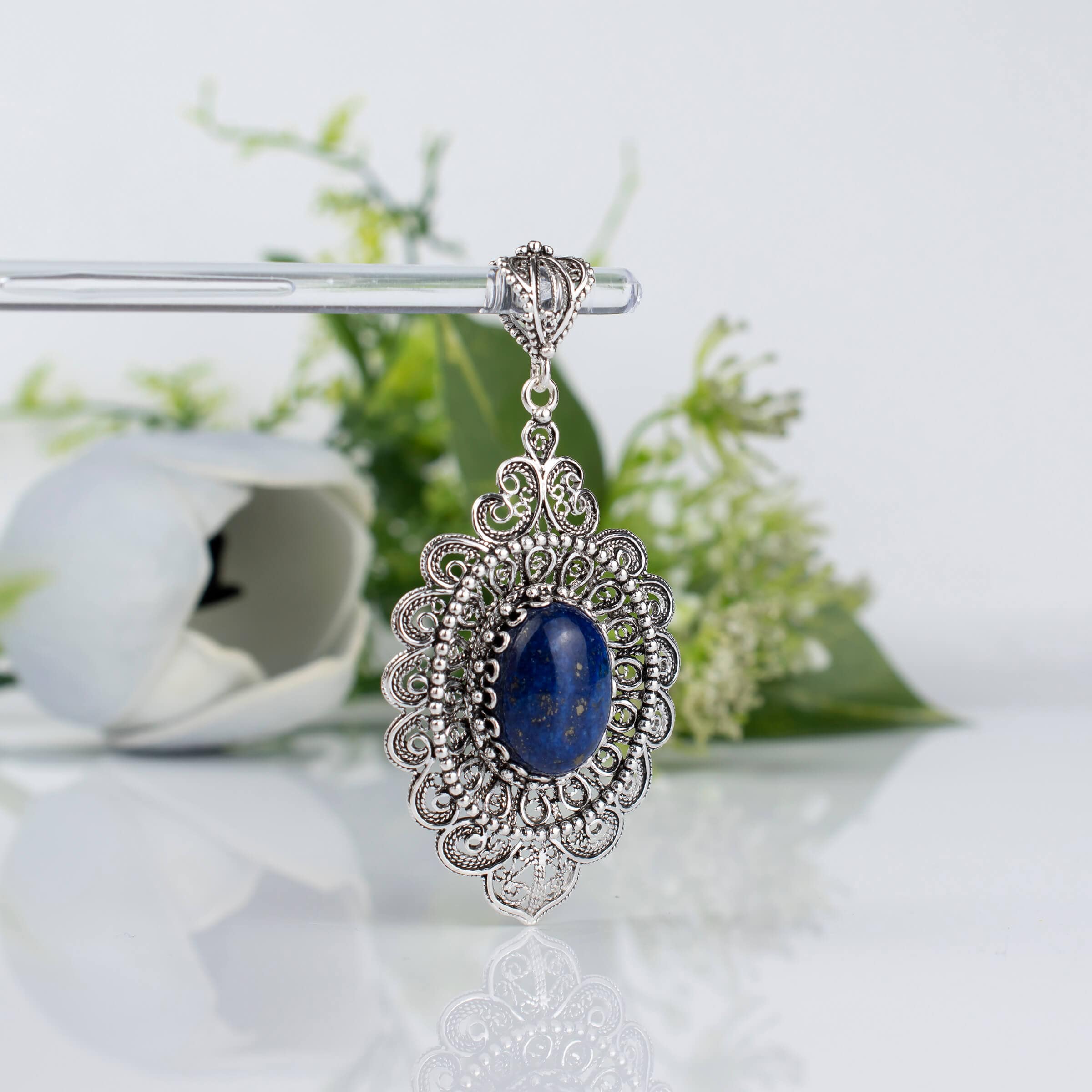 Elegant sterling silver pendant necklace featuring intricate floral filigree design and a stunning lapis lazuli gemstone.