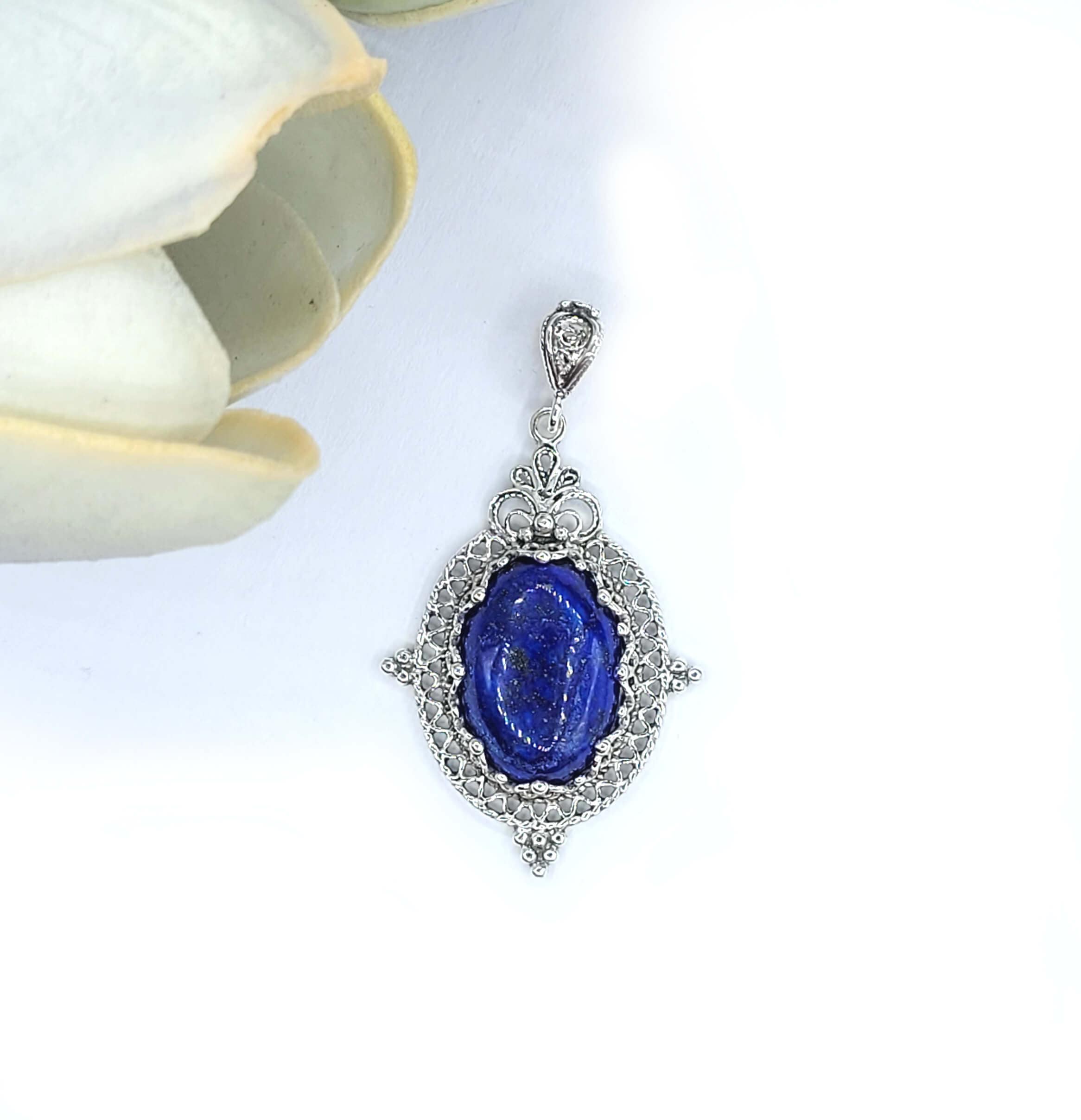 Elegant sterling silver filigree pendant necklace featuring a natural lapis lazuli gemstone in an oval shape.