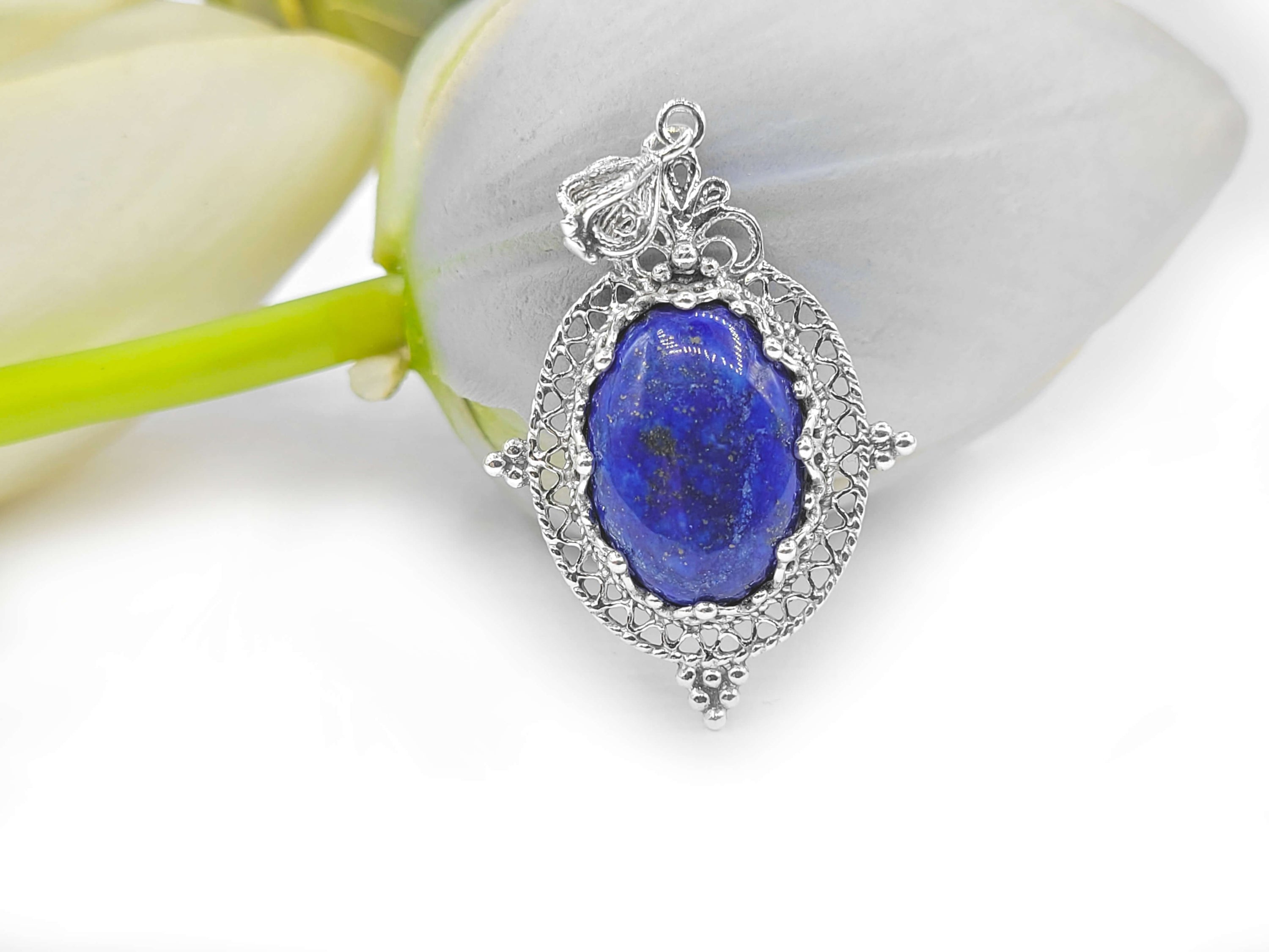 Elegant sterling silver filigree pendant necklace featuring a natural lapis lazuli gemstone in an oval shape.