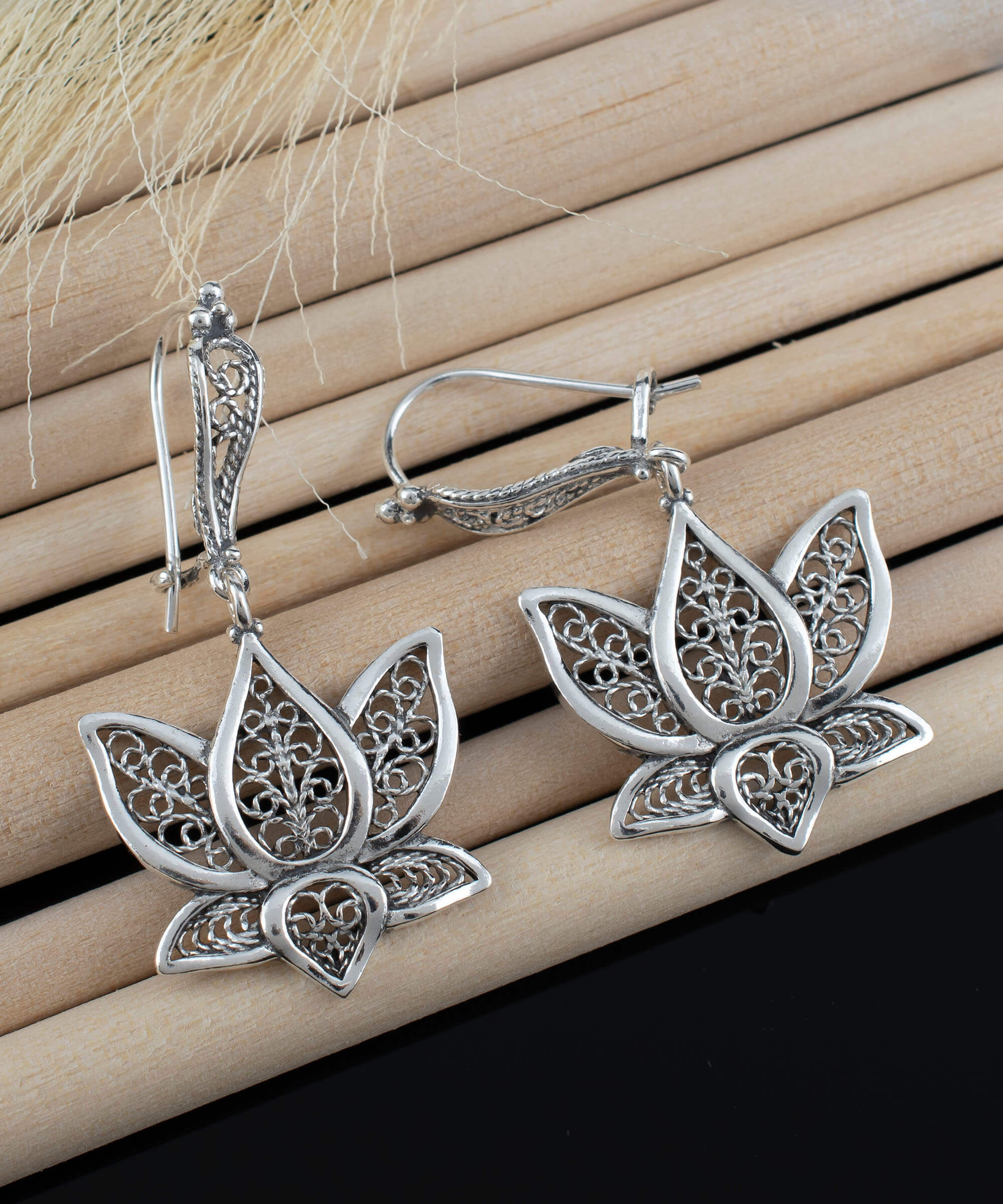 Elegant silver dangle drop earrings featuring intricate filigree art inspired by the lotus flower, showcasing craftsmanship and beauty.