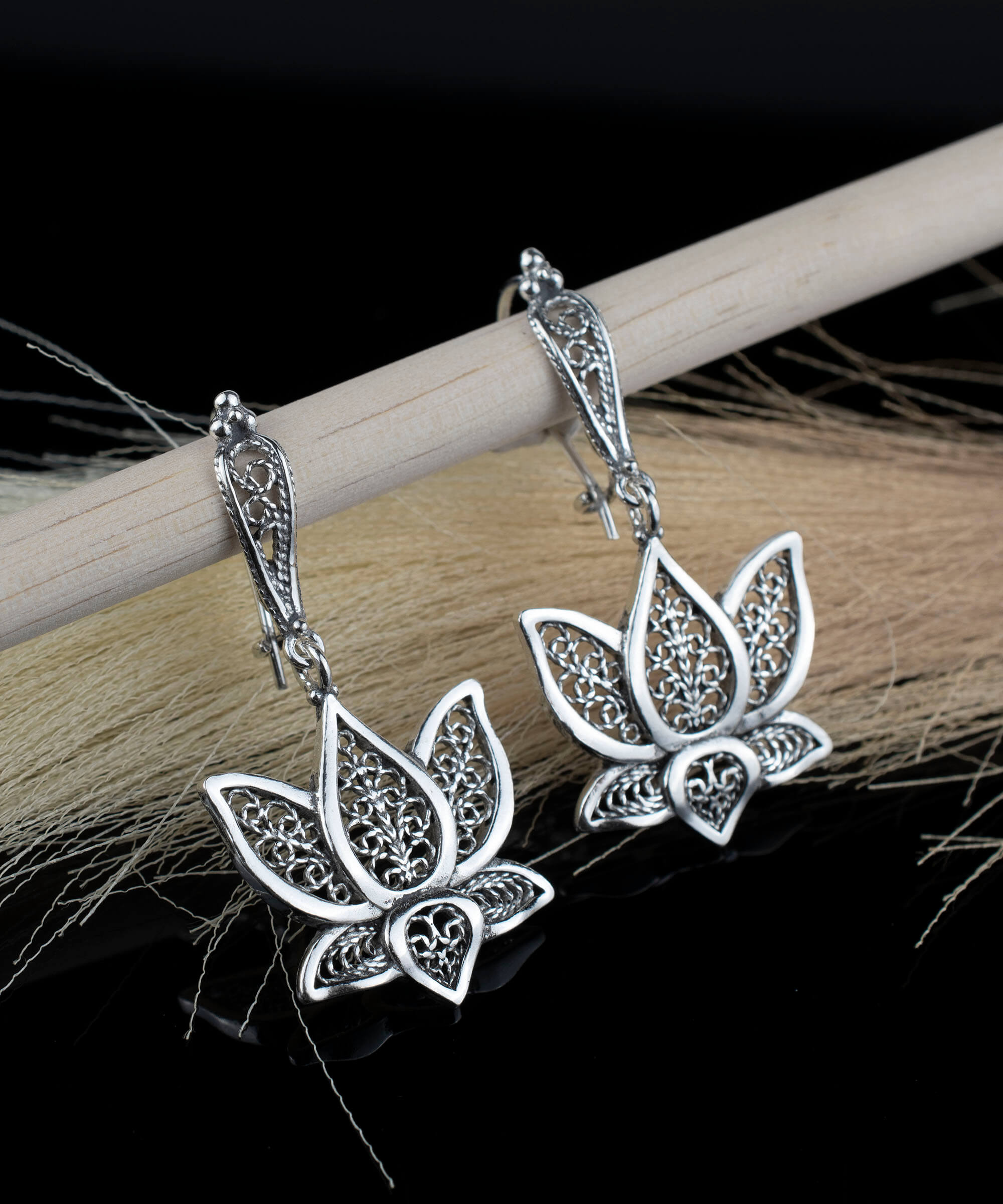 Elegant silver dangle drop earrings featuring intricate filigree art inspired by the lotus flower, showcasing craftsmanship and beauty.