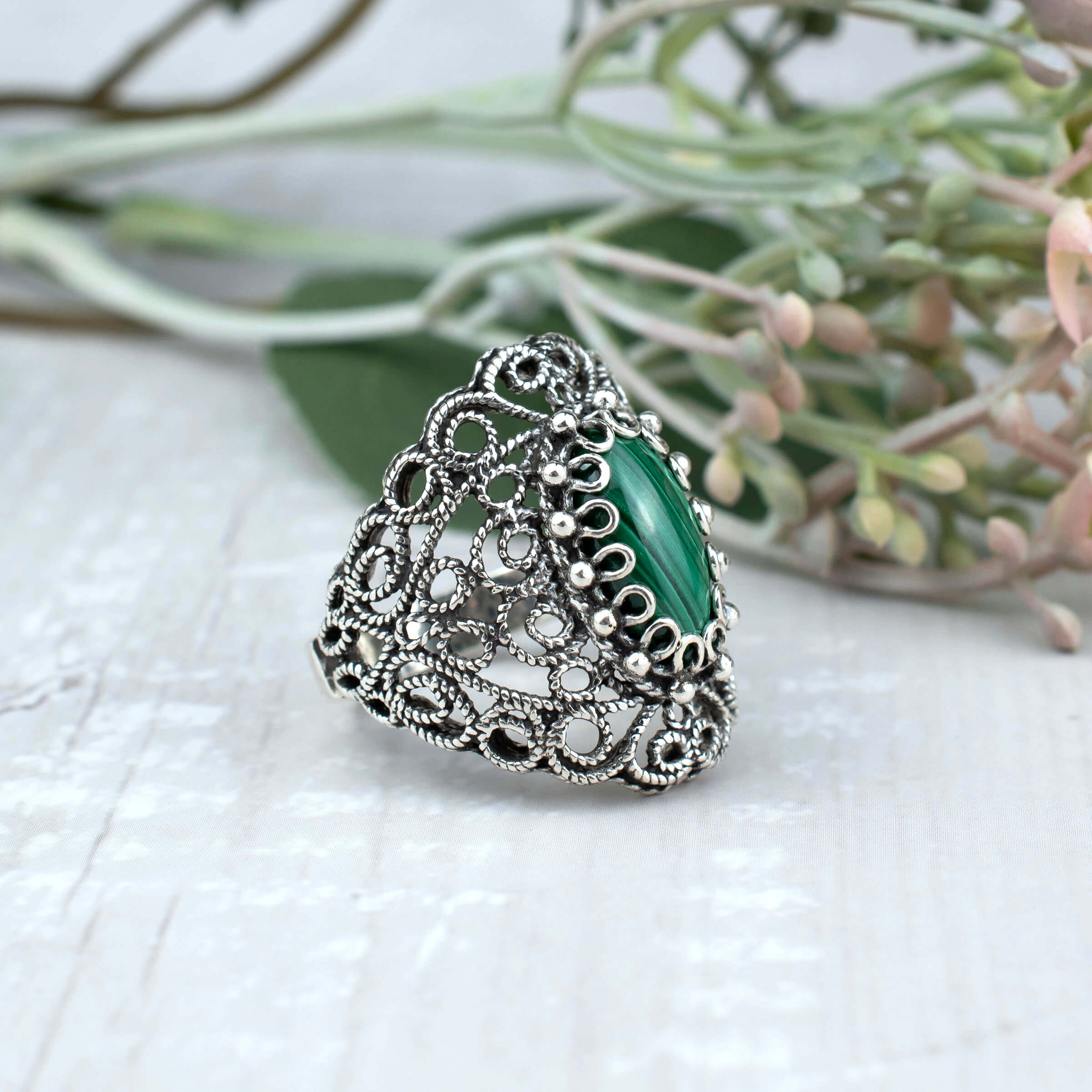 Handmade silver statement ring featuring a malachite gemstone with intricate filigree lace detailing, showcasing elegance and craftsmanship.