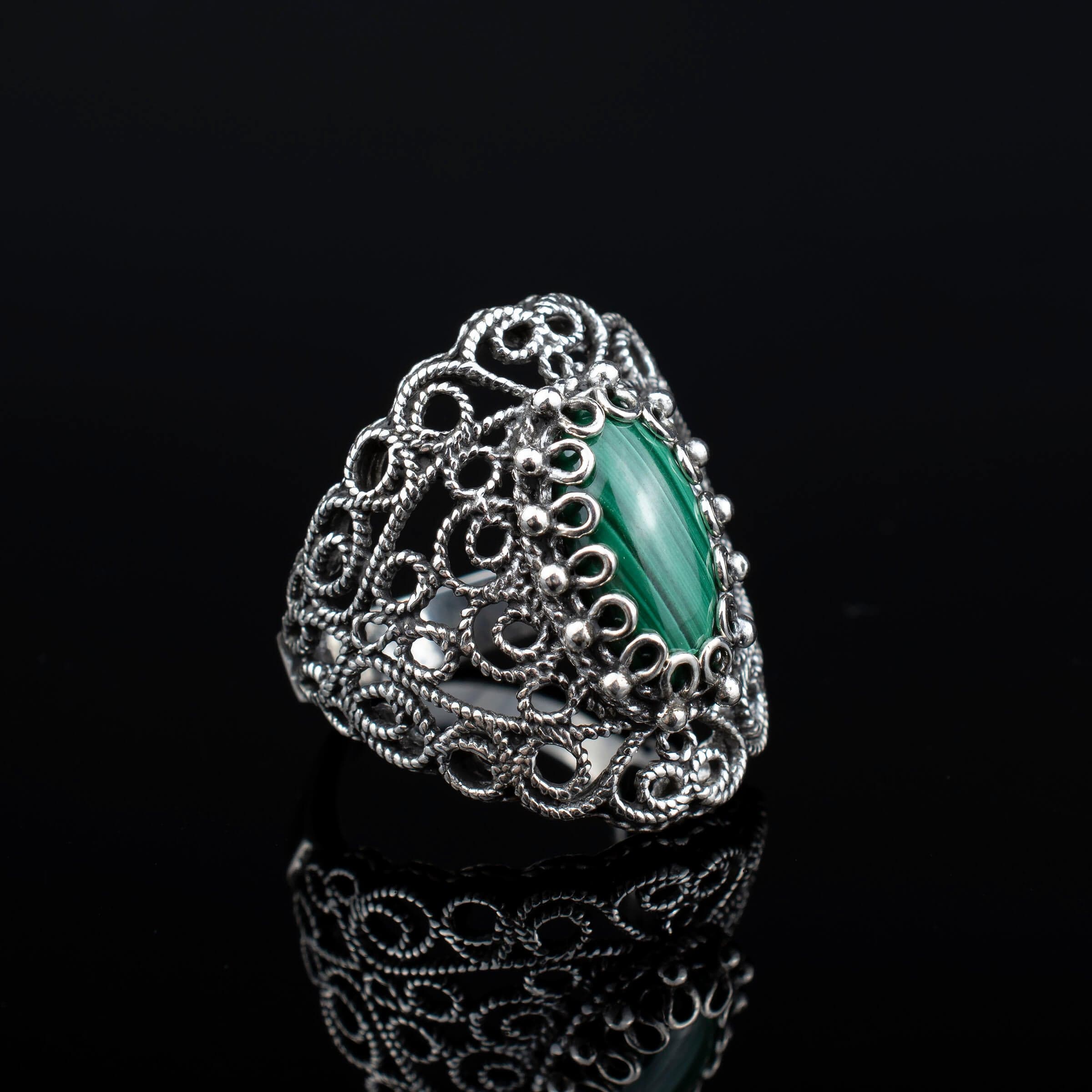 Handmade silver statement ring featuring a malachite gemstone with intricate filigree lace detailing, showcasing elegance and craftsmanship.