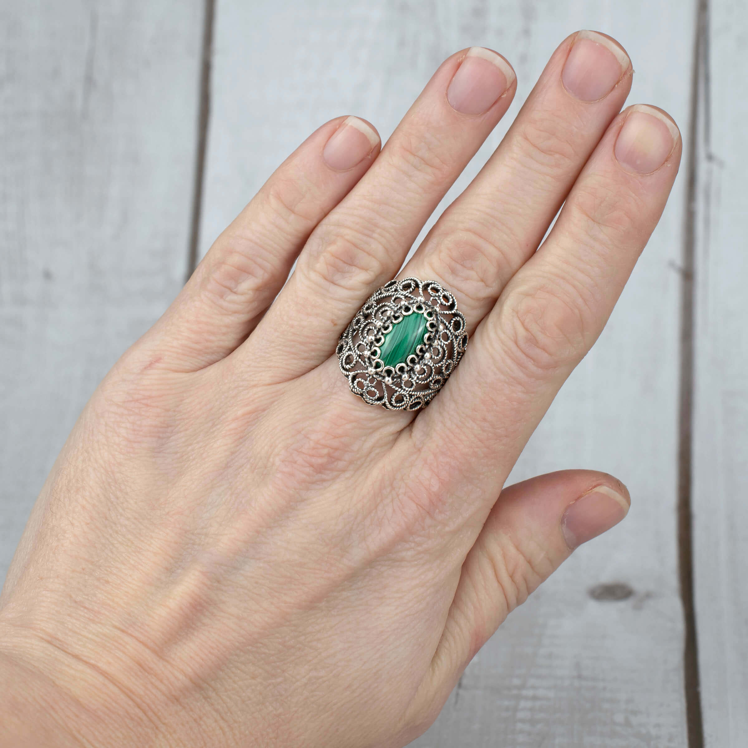 Handmade silver statement ring featuring a malachite gemstone with intricate filigree lace detailing, showcasing elegance and craftsmanship.