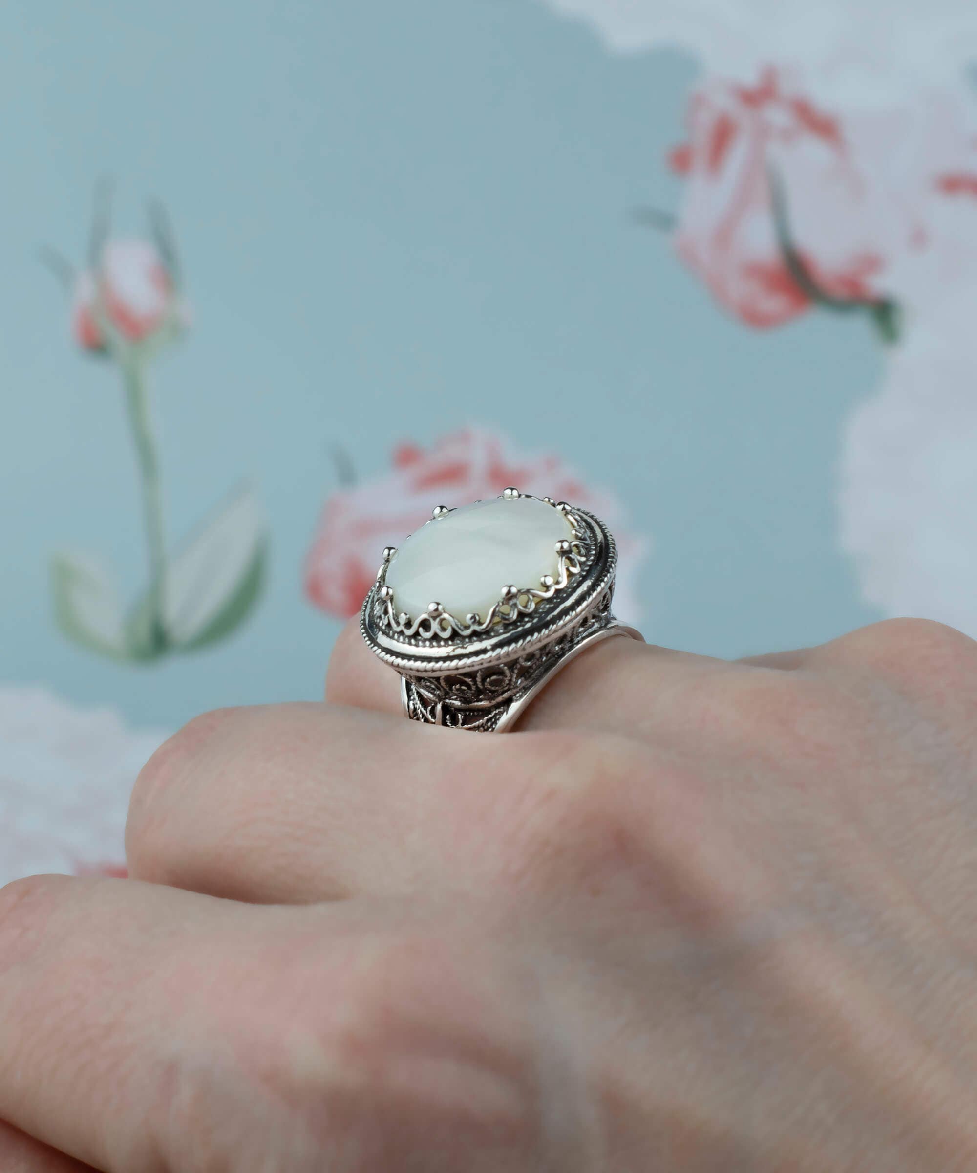 A stunning sterling silver ring featuring a round mother of pearl gemstone with intricate filigree design, perfect for bold statement wear.