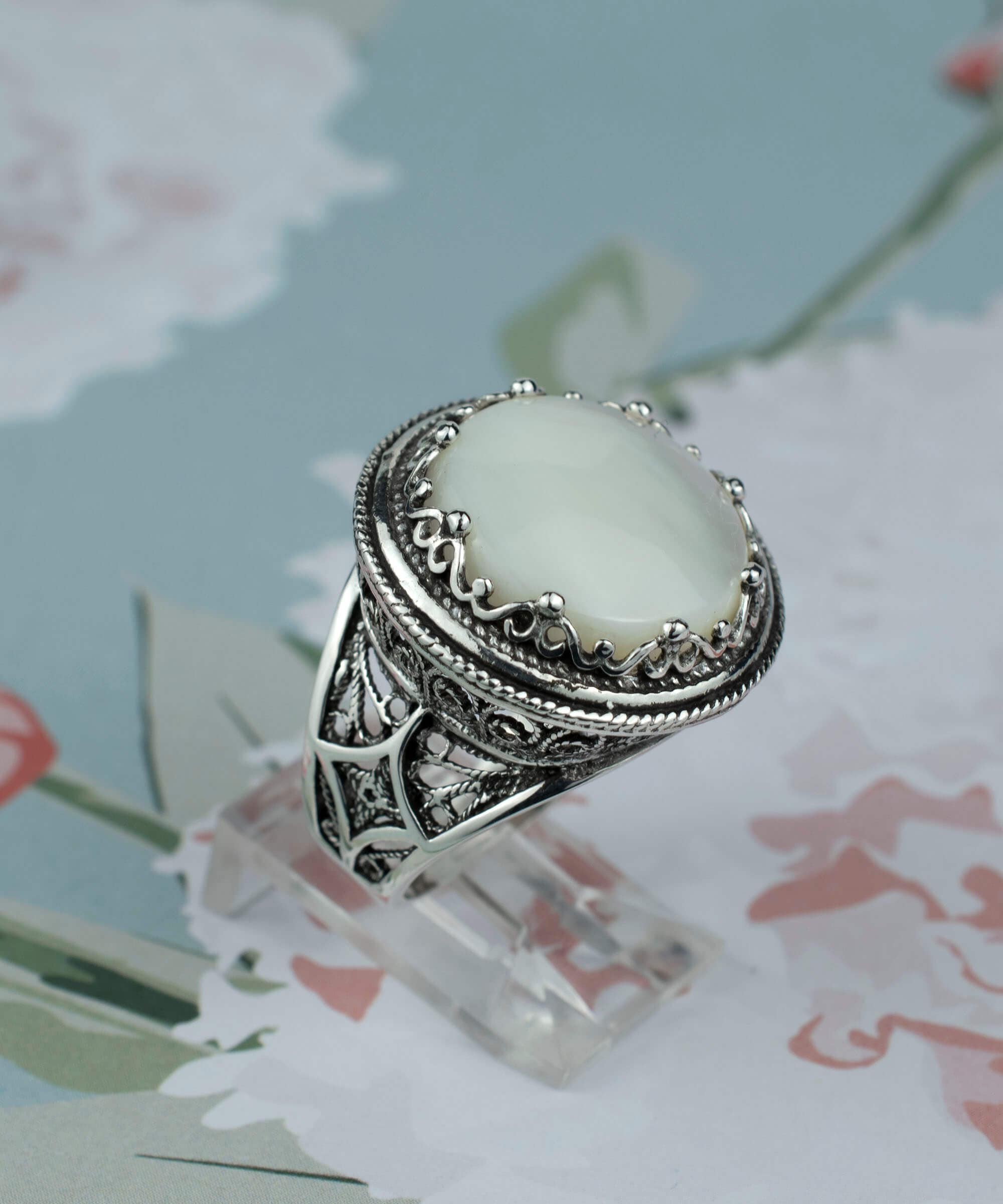 A stunning sterling silver ring featuring a round mother of pearl gemstone with intricate filigree design, perfect for bold statement wear.