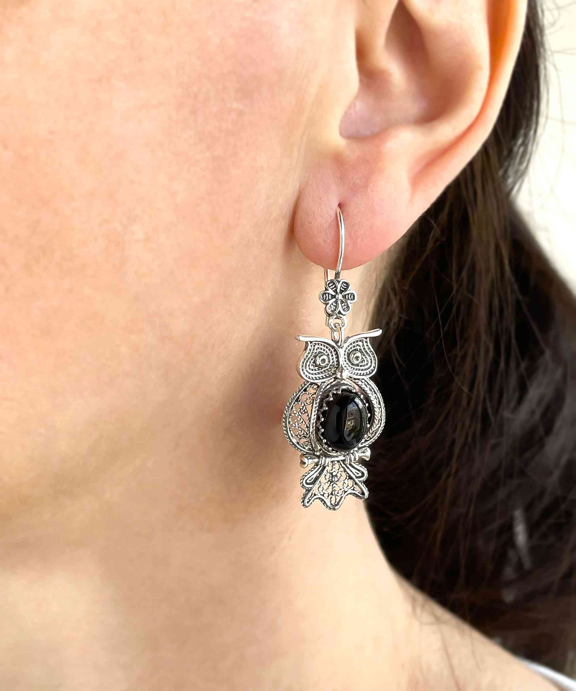 Elegant silver dangle earrings featuring an owl design with intricate filigree work and a central Black Onyx gemstone.