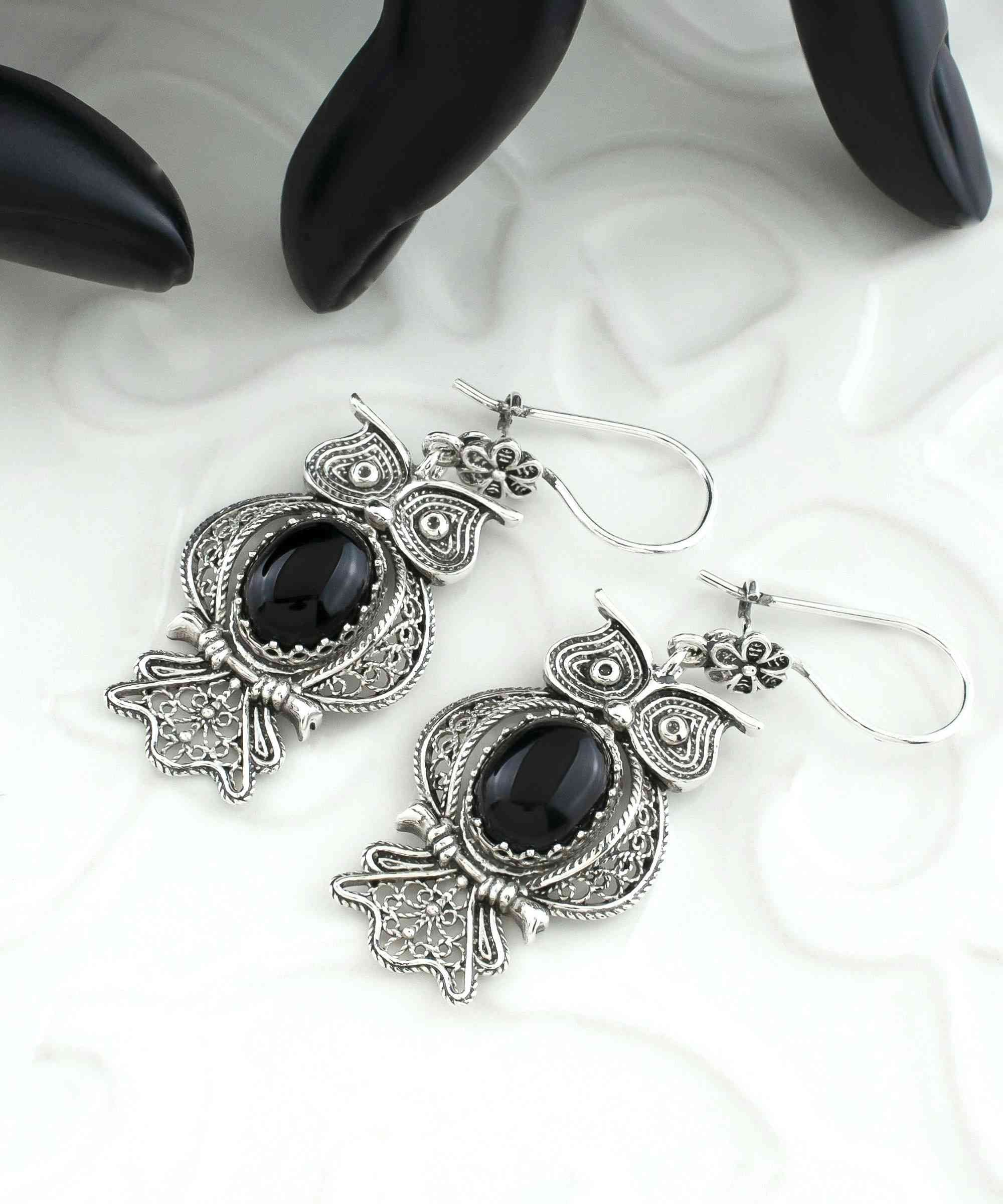 Elegant silver dangle earrings featuring an owl design with intricate filigree work and a central Black Onyx gemstone.