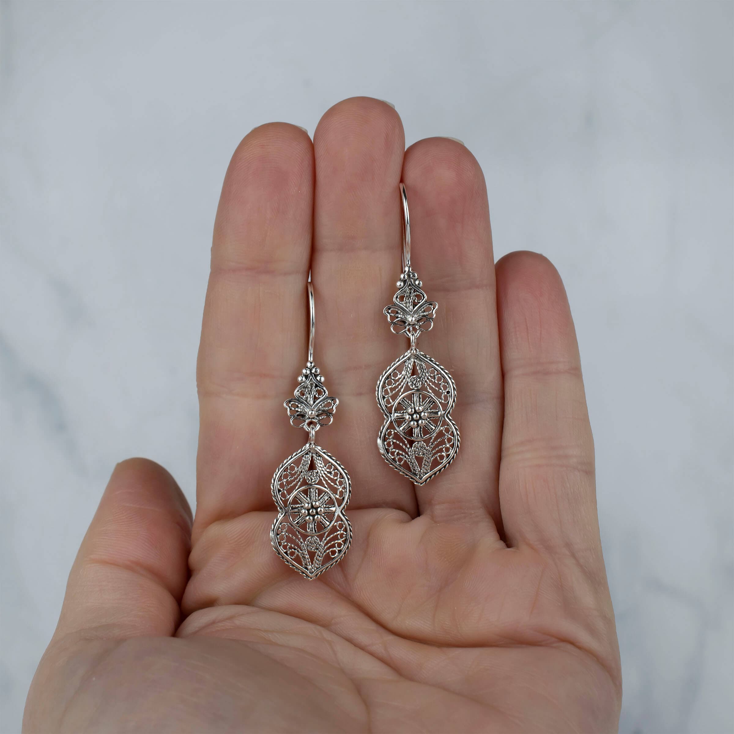 Elegant sterling silver dangle drop earrings featuring intricate paisley filigree design, showcasing a vintage look and polished shine.