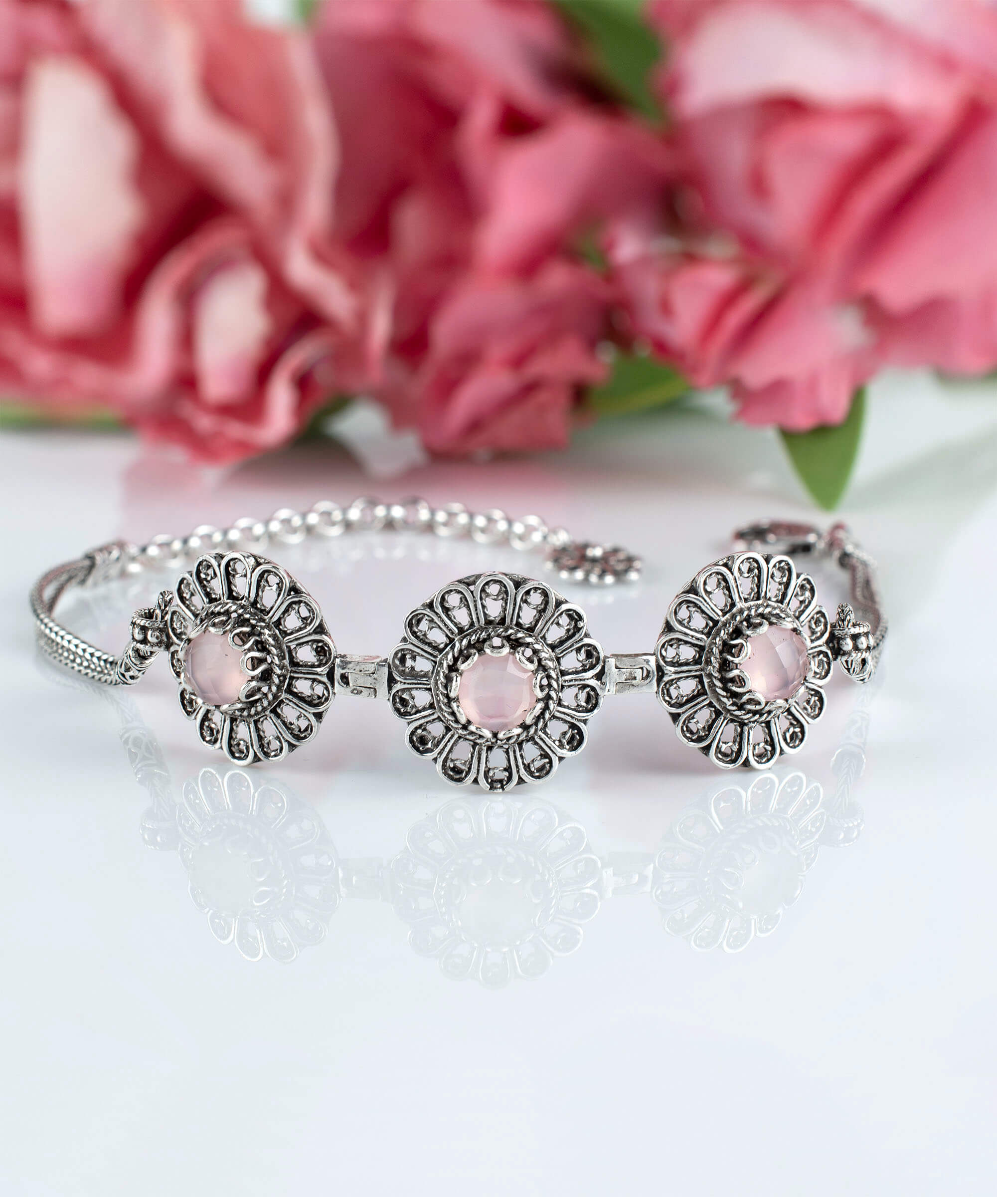 Elegant sterling silver link bracelet featuring intricate filigree art and a double-sided faceted pink chalcedony gemstone.