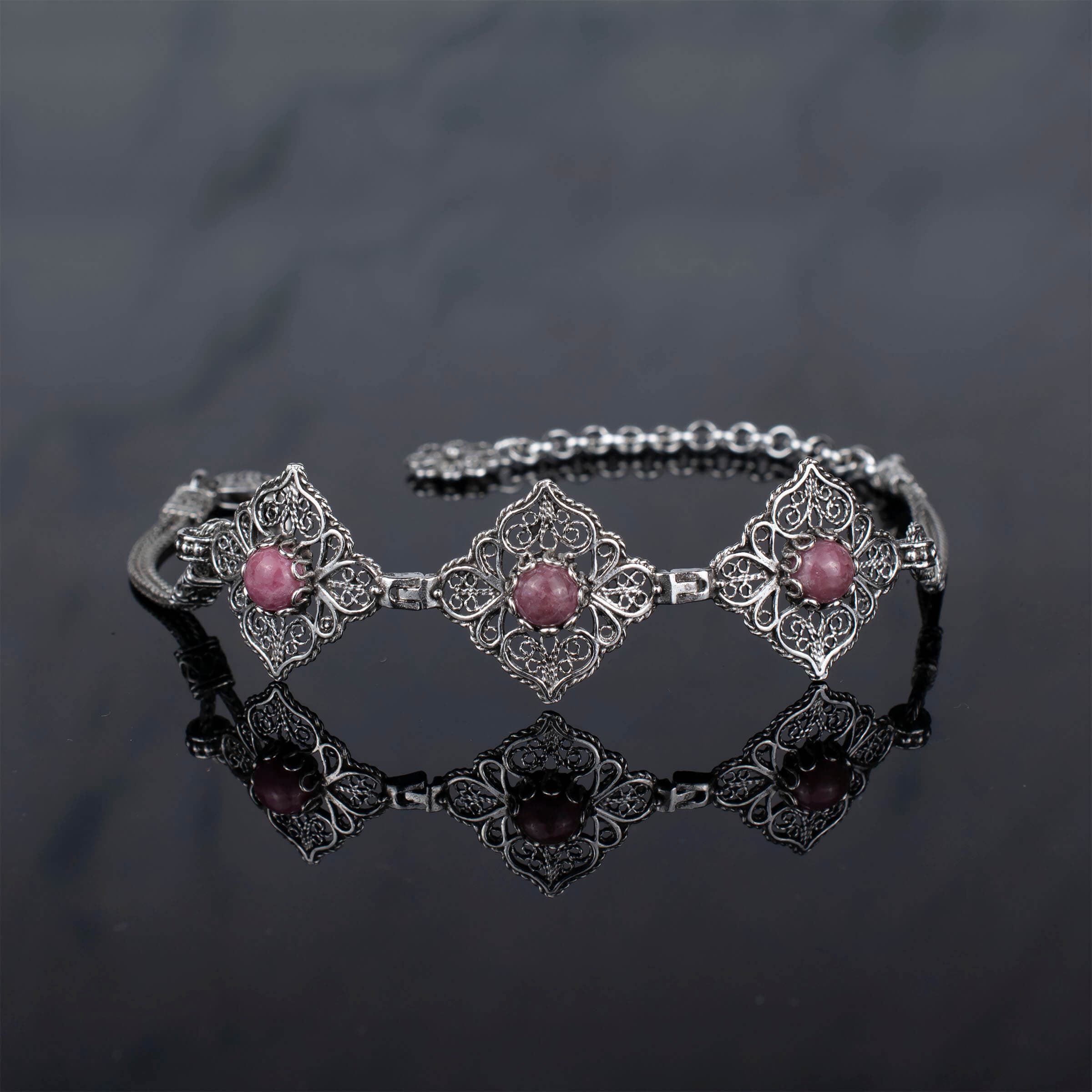 Elegant adjustable silver link bracelet featuring filigree art and a natural rhodonite gemstone, beautifully crafted for women.