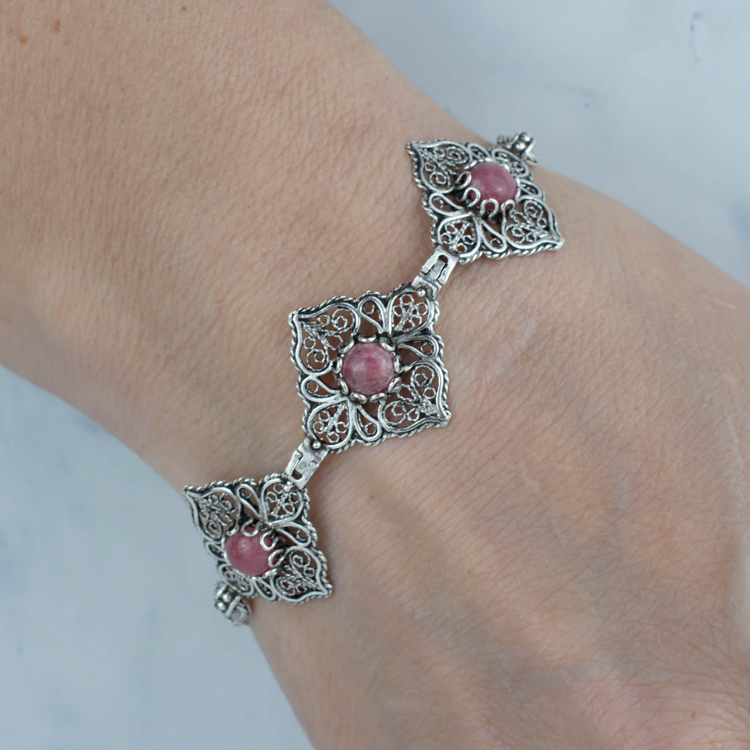 Elegant adjustable silver link bracelet featuring filigree art and a natural rhodonite gemstone, beautifully crafted for women.