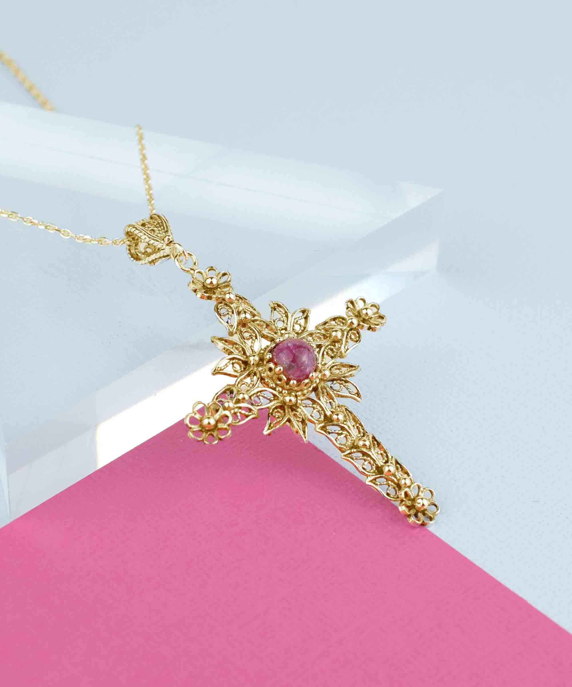 Gold plated silver cross pendant featuring a Rhodonite gemstone with intricate filigree art design.