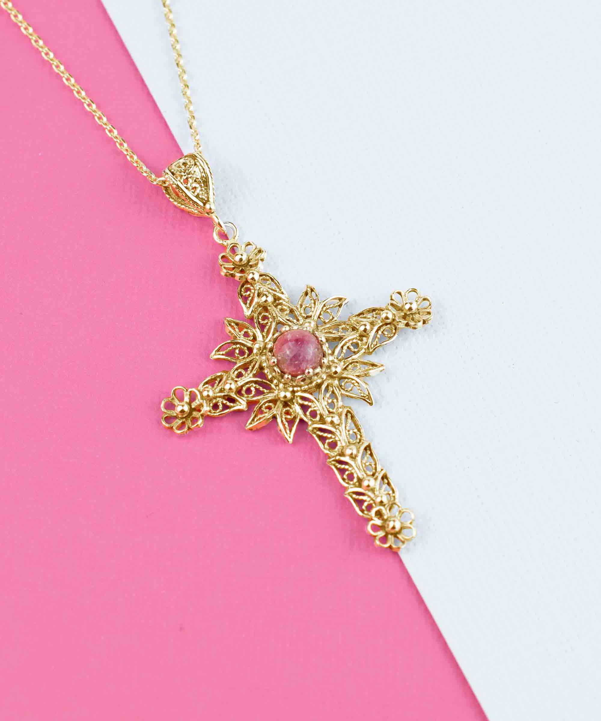 Gold plated silver cross pendant featuring a Rhodonite gemstone with intricate filigree art design.