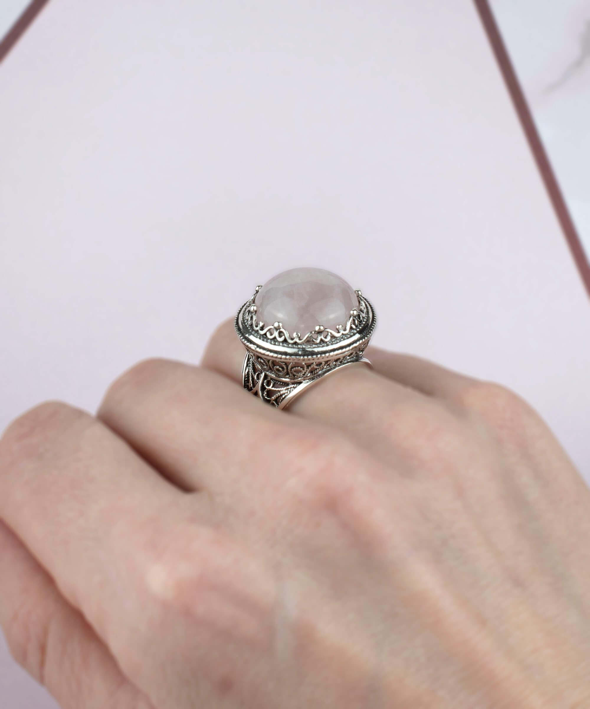 A stunning sterling silver filigree ring featuring a round cut rose quartz gemstone, showcasing intricate metalwork and a polished finish.