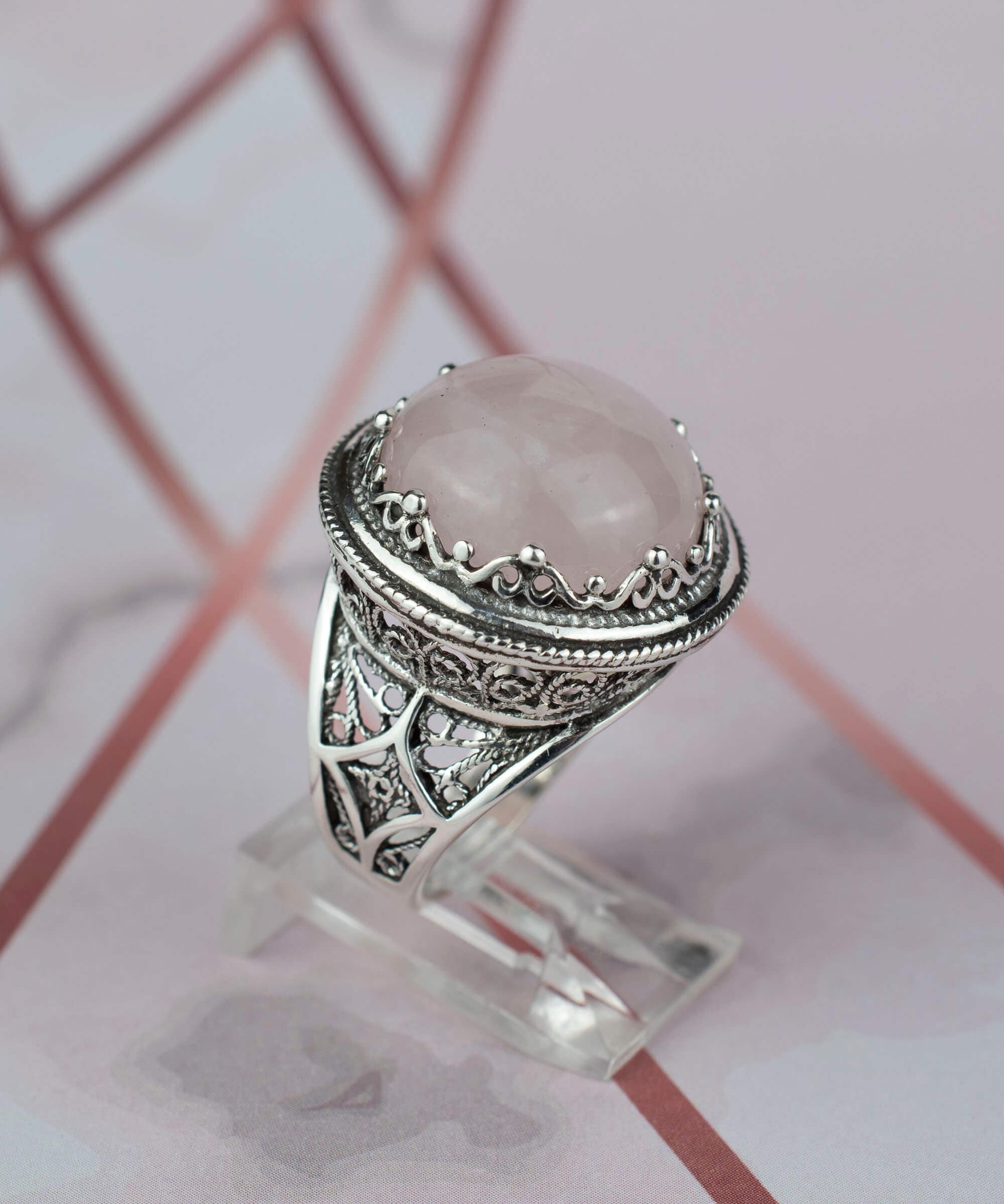 A stunning sterling silver filigree ring featuring a round cut rose quartz gemstone, showcasing intricate metalwork and a polished finish.