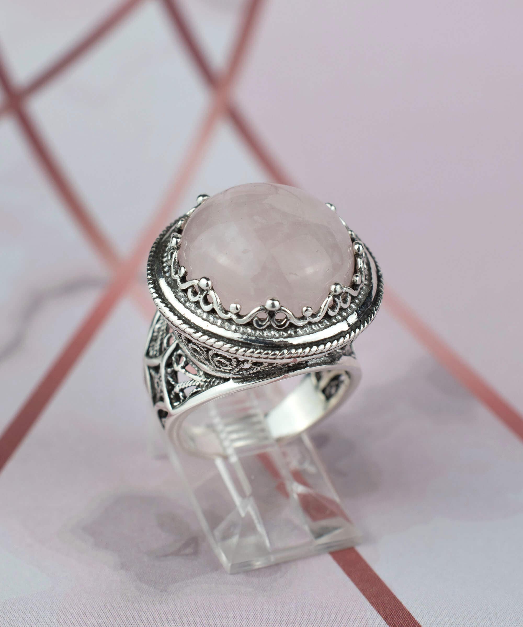 A stunning sterling silver filigree ring featuring a round cut rose quartz gemstone, showcasing intricate metalwork and a polished finish.