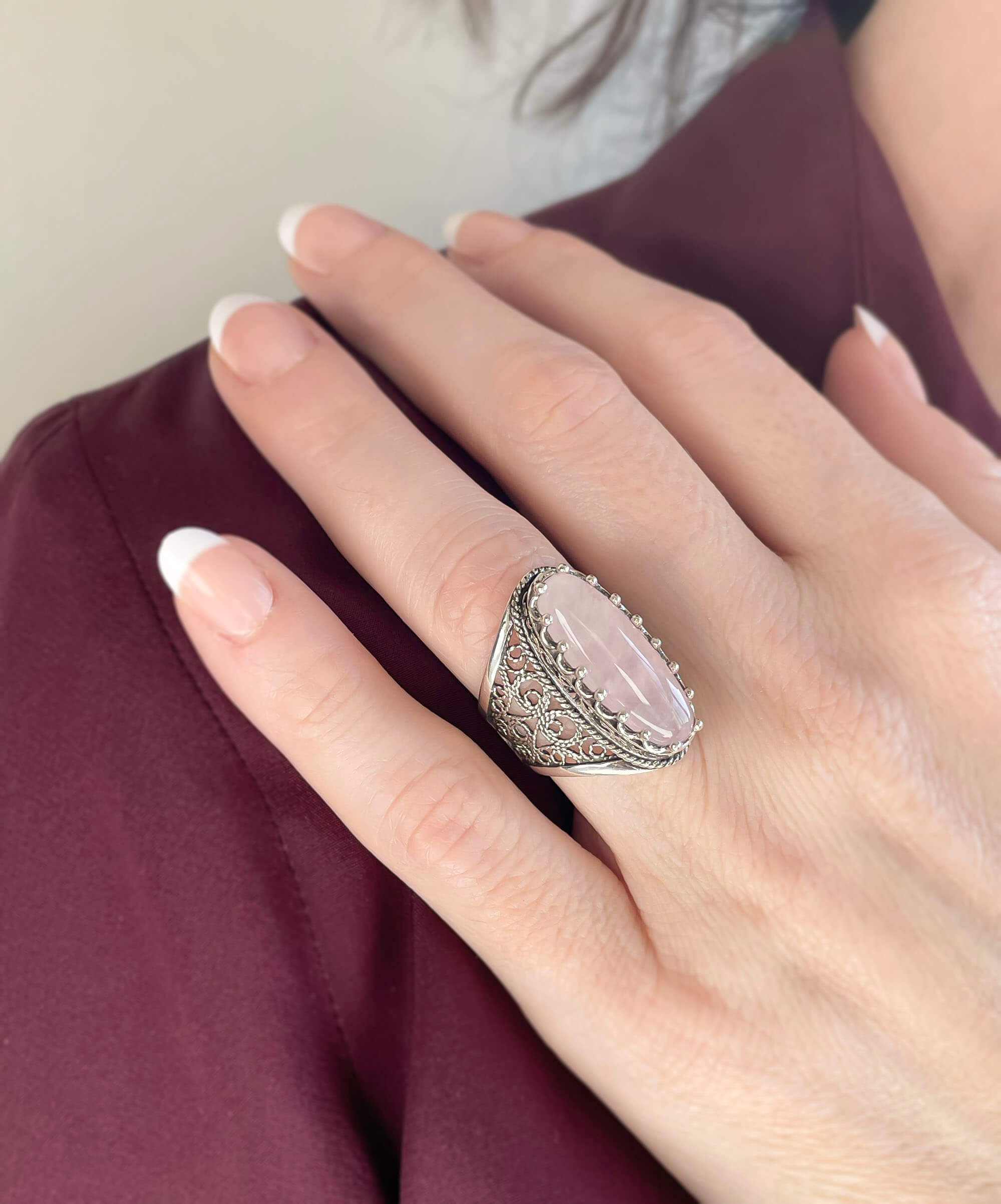 A stunning long statement ring featuring a natural rose quartz gemstone set in intricately designed sterling silver filigree.