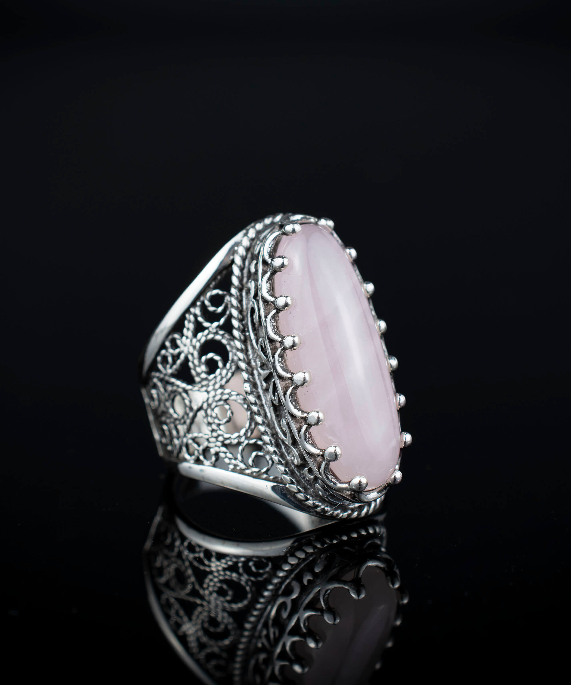 A stunning long statement ring featuring a natural rose quartz gemstone set in intricately designed sterling silver filigree.